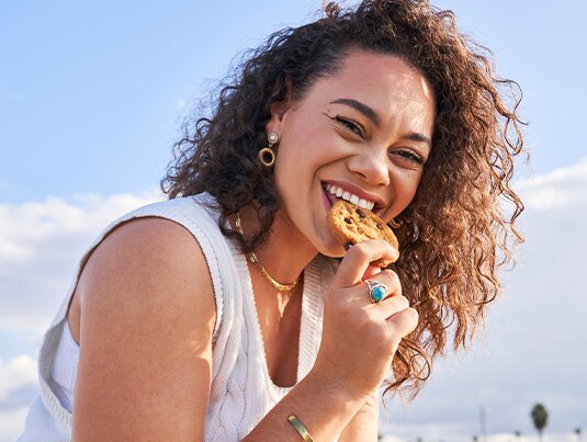 Smiling girl eating a chocolate chip cookie.
