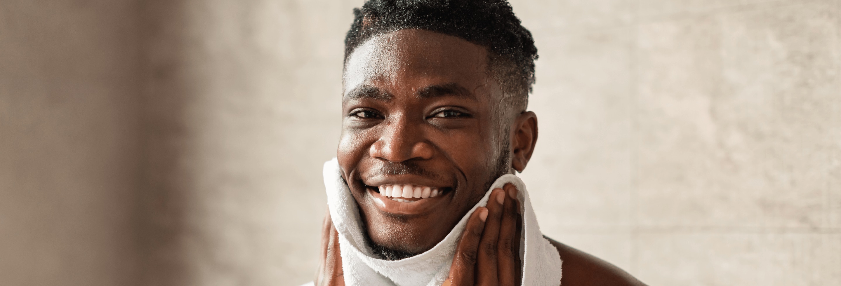 Young African American man drying off his face after cleansing it with face wash
