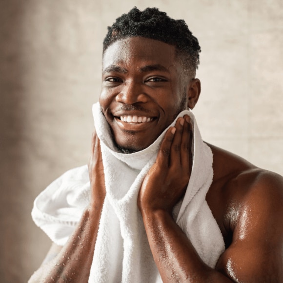 Young African American man drying off his face after cleansing it with face wash