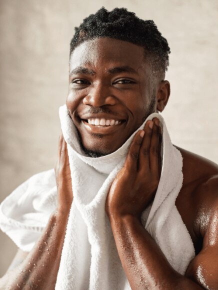 Young African American man drying off his face after cleansing it with face wash
