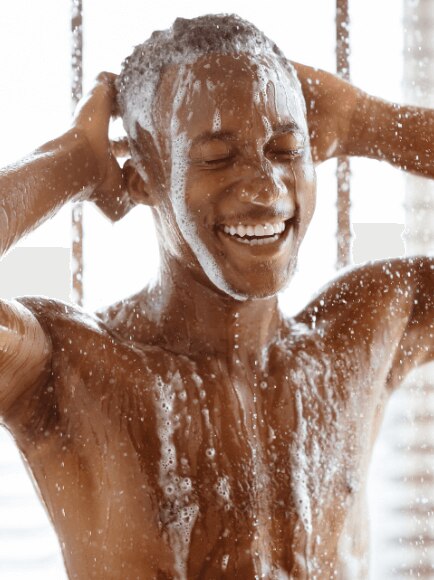 Young African American man washing his hair and body under a hot shower