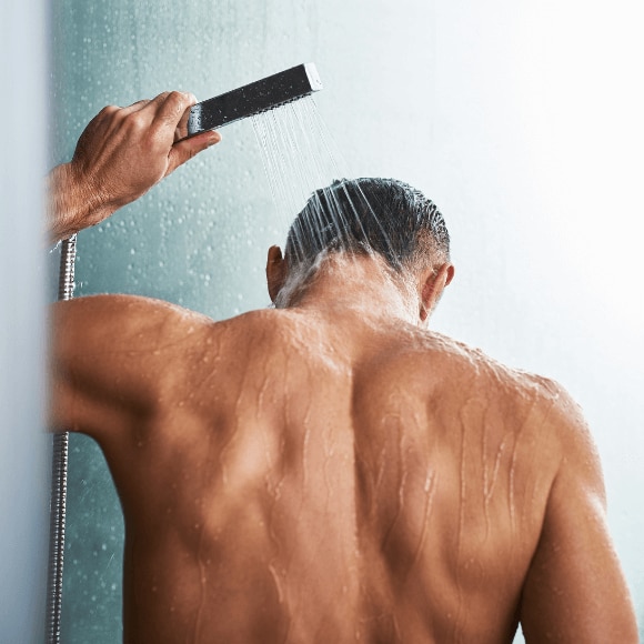Man takes a cold shower with a handheld shower