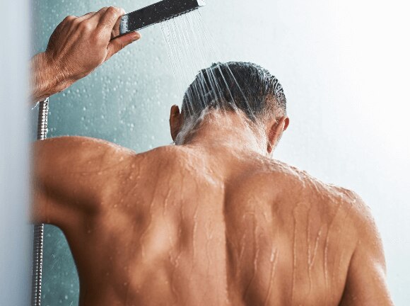 Man takes a cold shower with a handheld shower