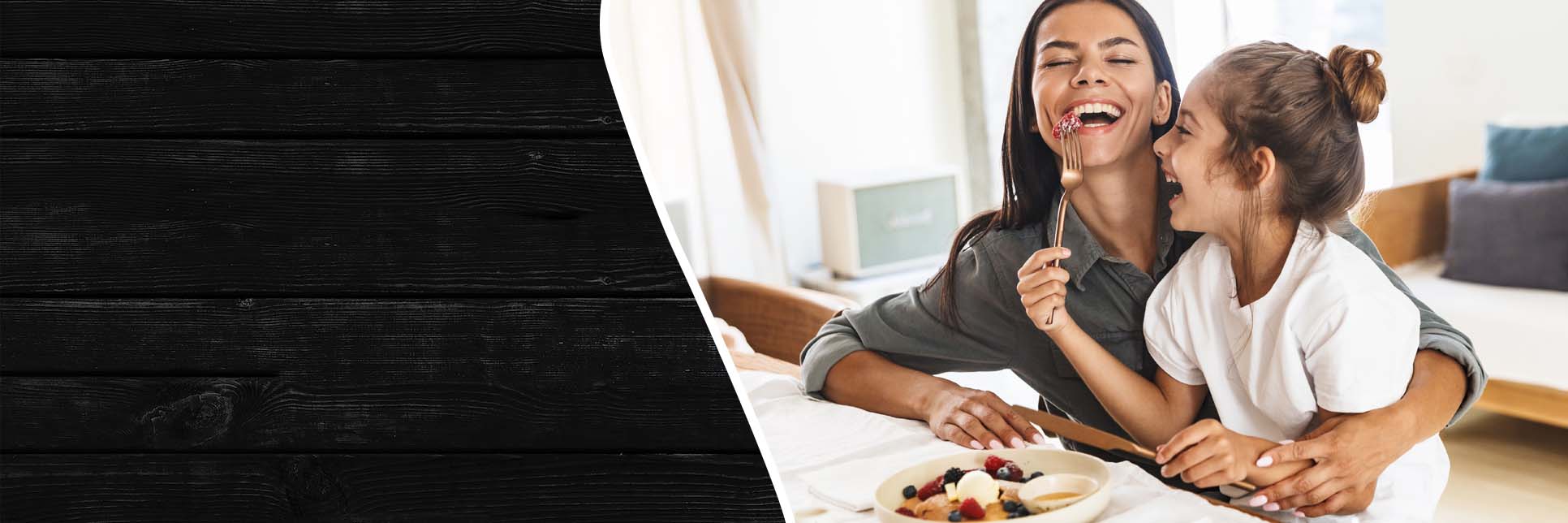 Mother and daughter having fun while having breakfast