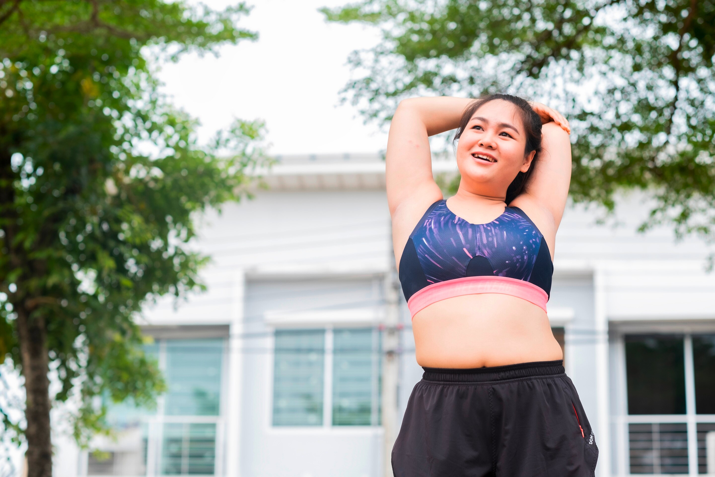 Woman in athleisure stretching her arms outdoors.
