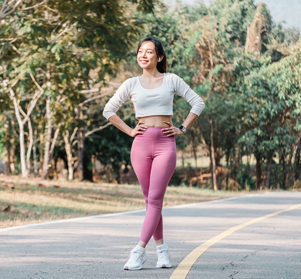 Woman in leggings and cropped top posing on road.