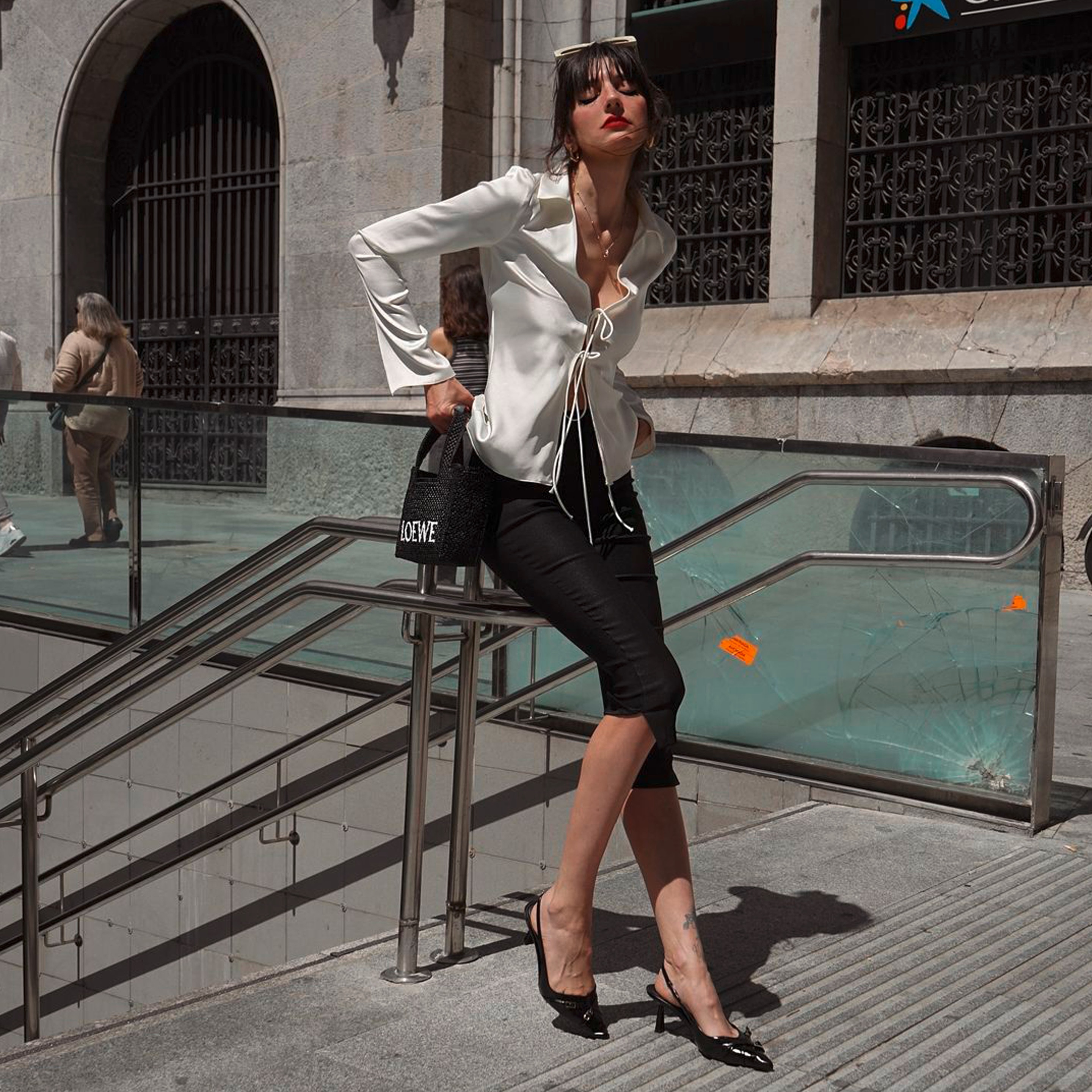 A portrait of woman wearing black capri pants and white silk shirt.