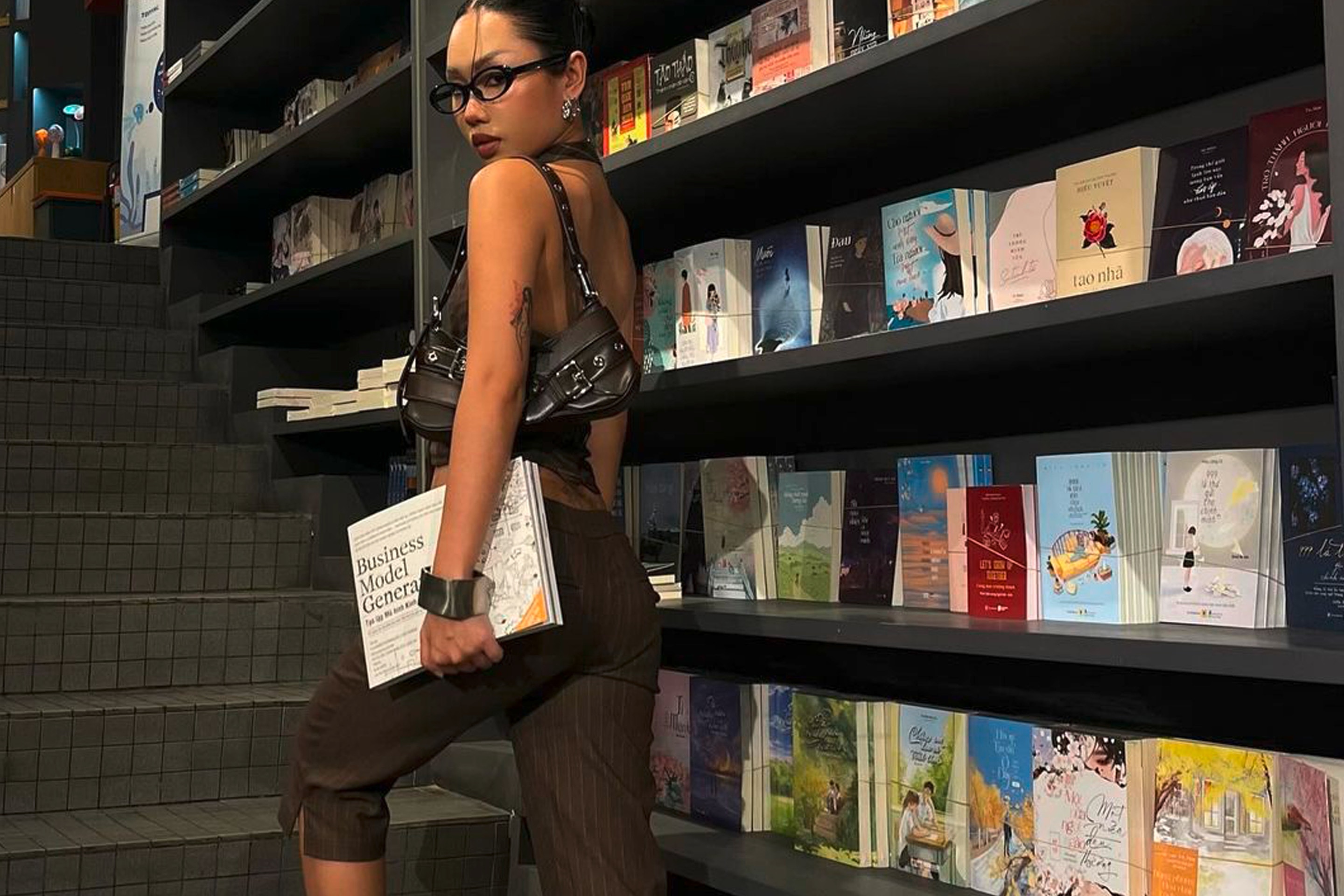 Woman in capri pants and heels walking up the stairs in a bookstore.