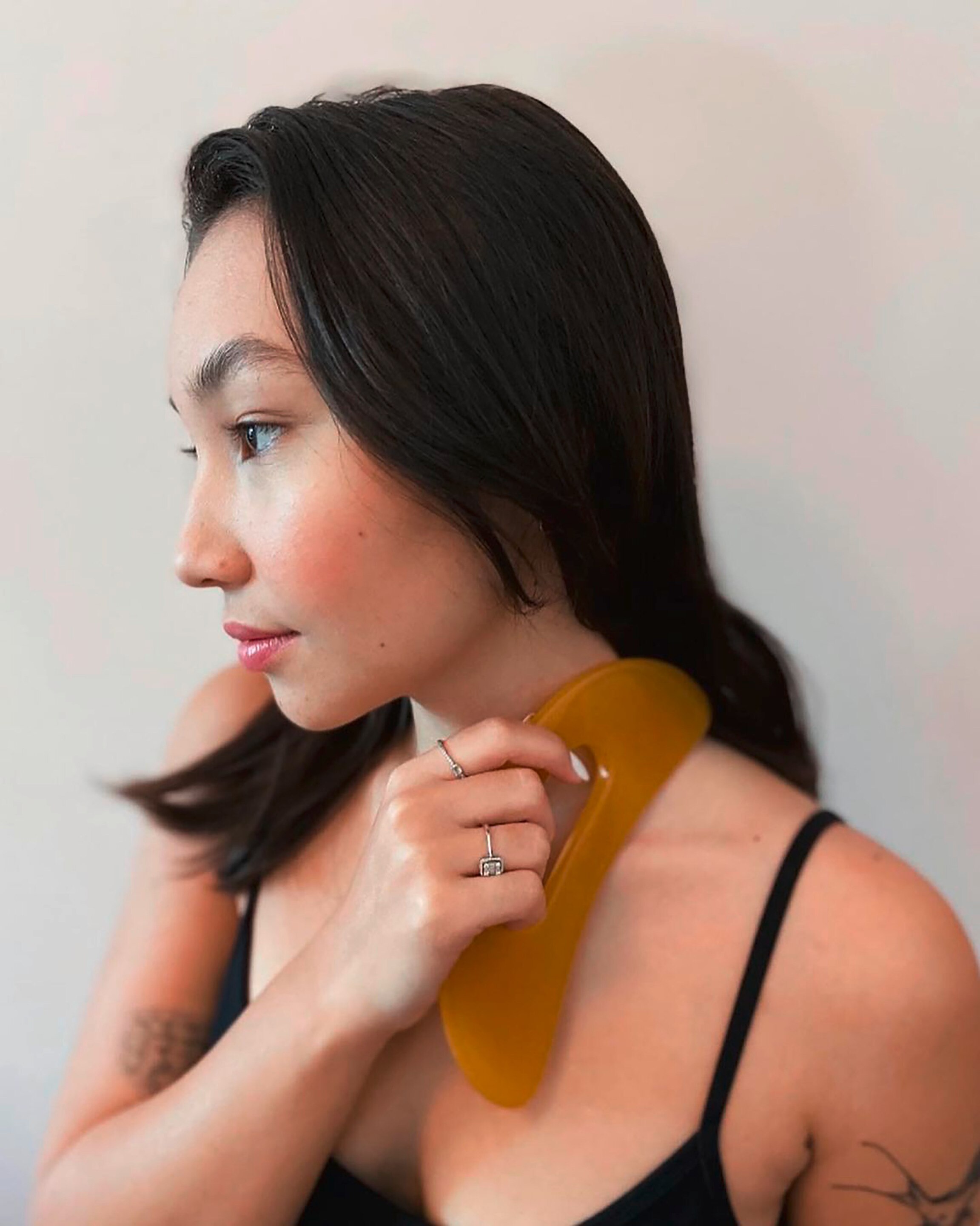 Woman massaging her body with a big gua sha.