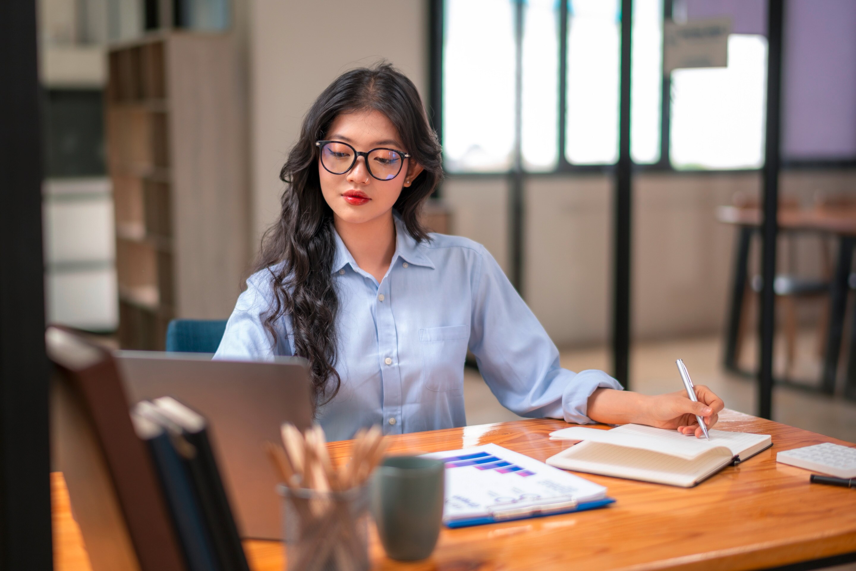 Woman wearing black-rimmed glasses and a bold lip color.