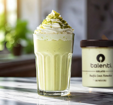 Glass of pistachio milkshake on a marble table.