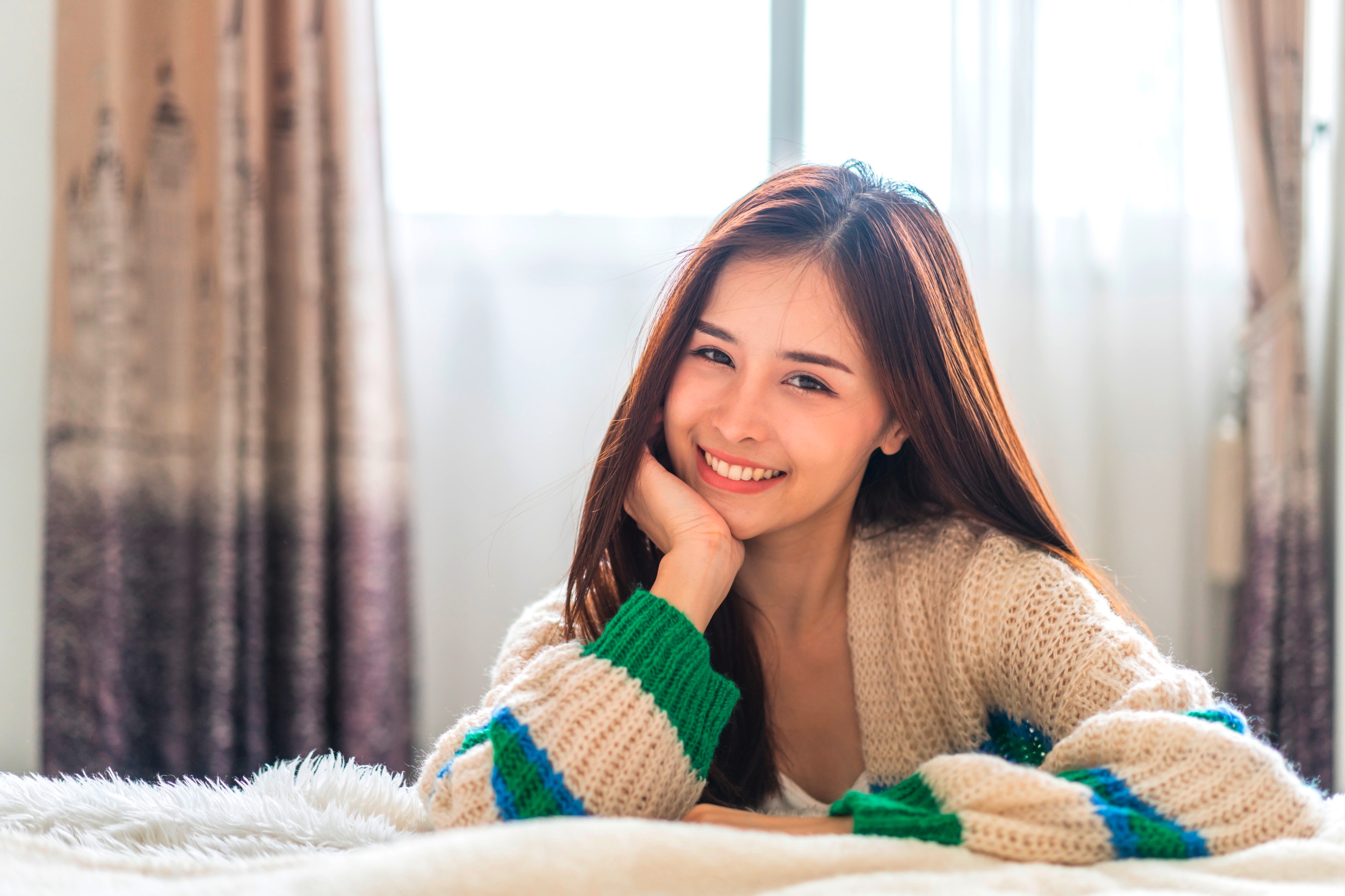 A portrait of woman in a knitted cardigan smiling at the camera.
