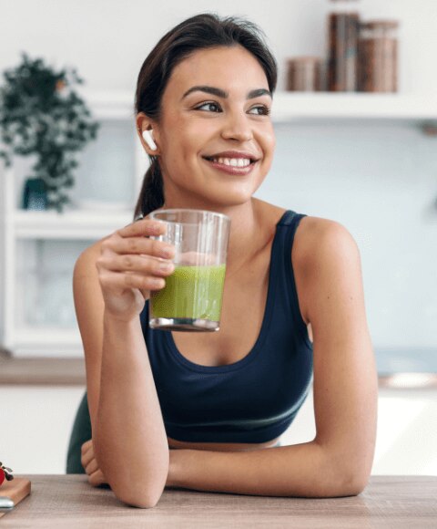 Young woman drinking a spinach and avocado smoothie to replenish electrolytes after a workout
