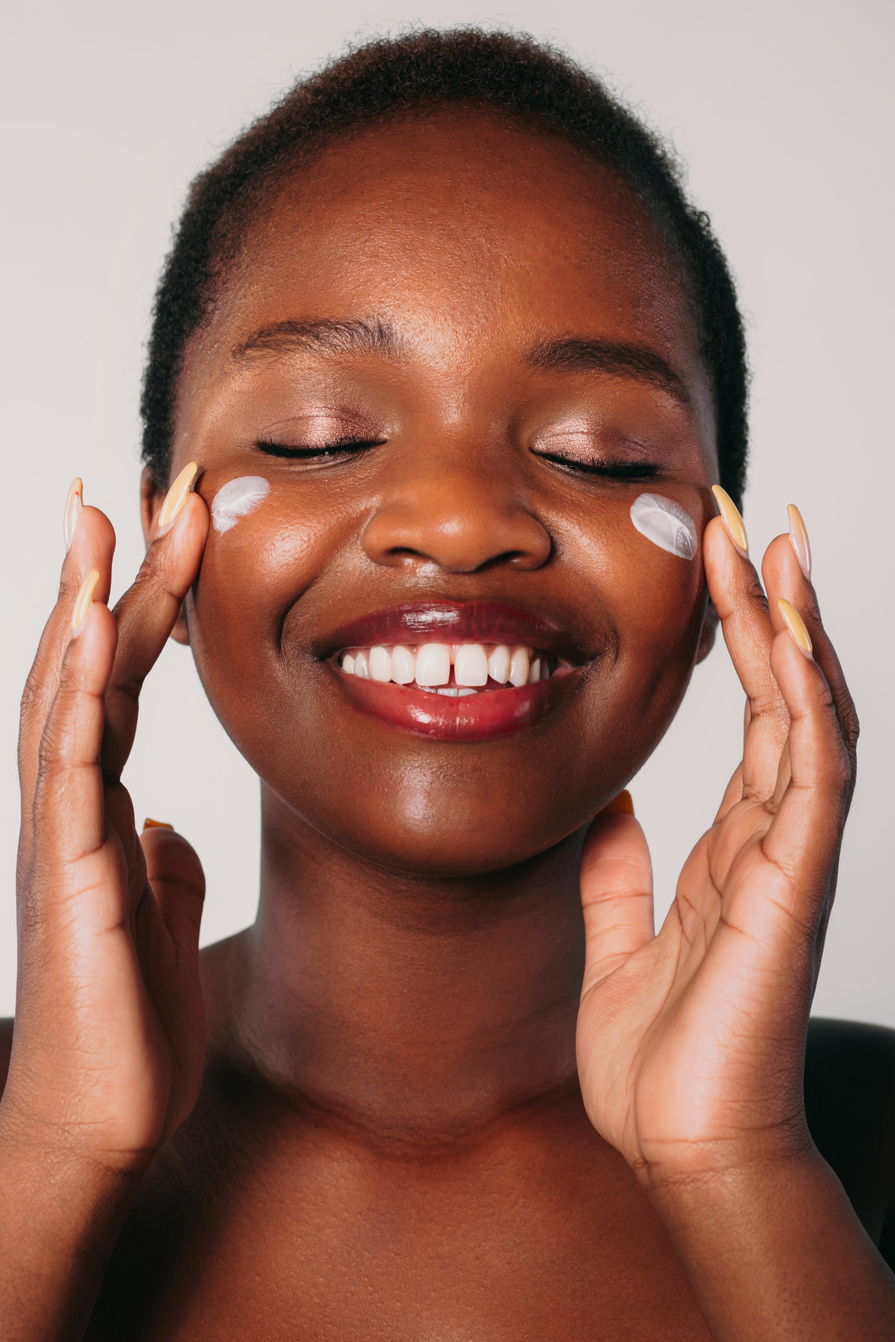 Woman layering skincare products on her face at nighttime