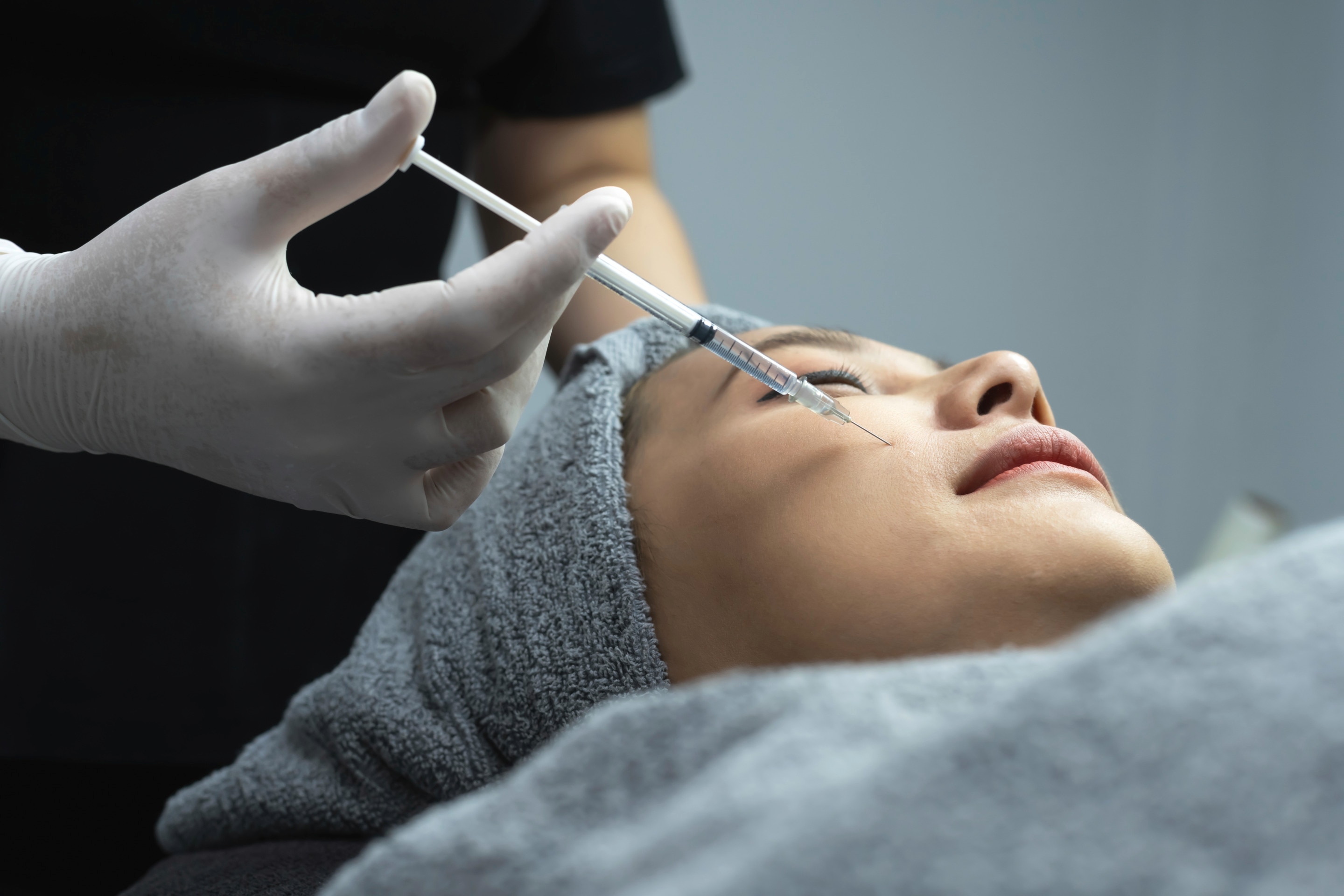 Close-up of Asian woman getting facial injections from facialist.