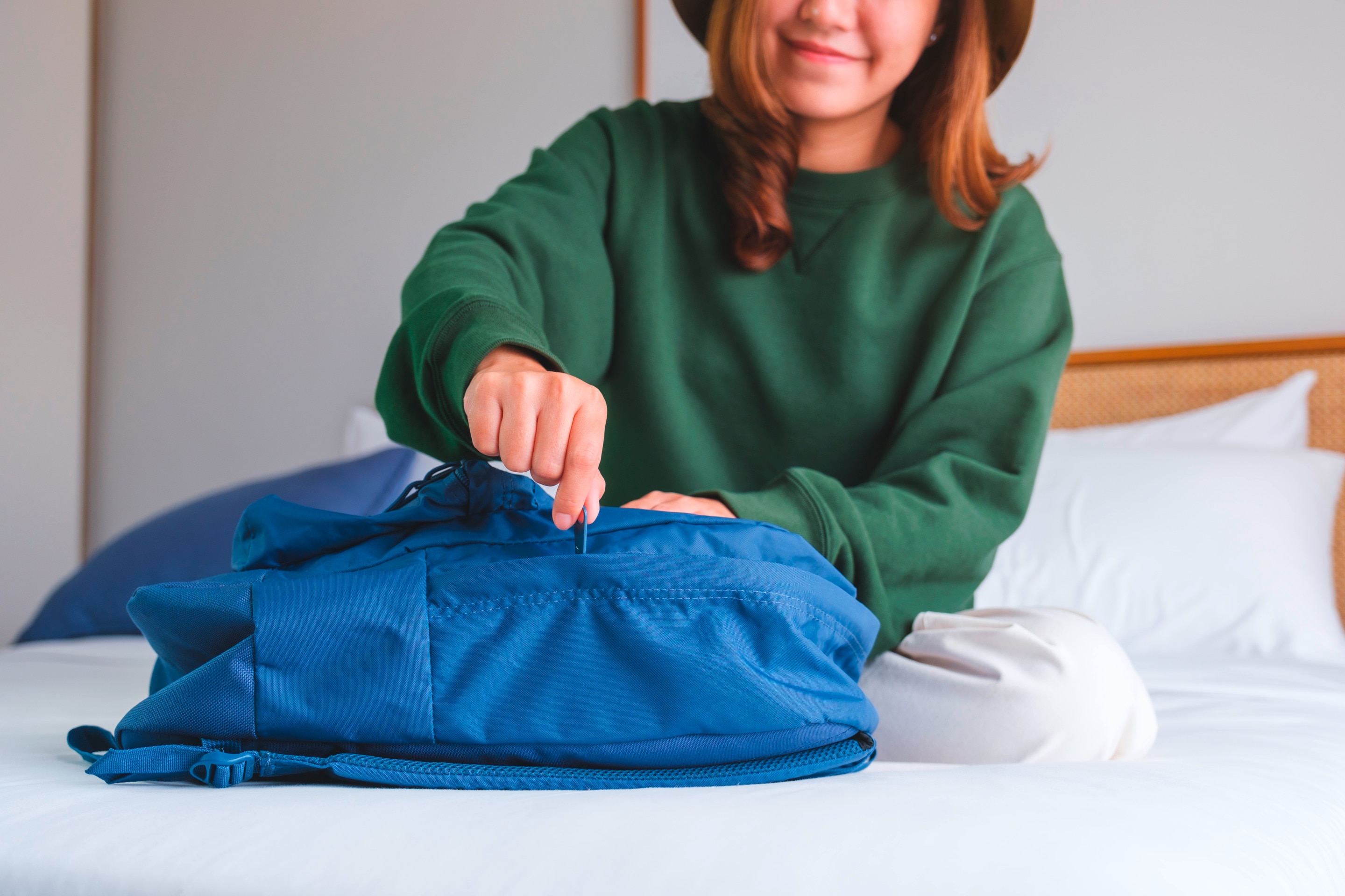 Smiling woman packing her blue backpack.
