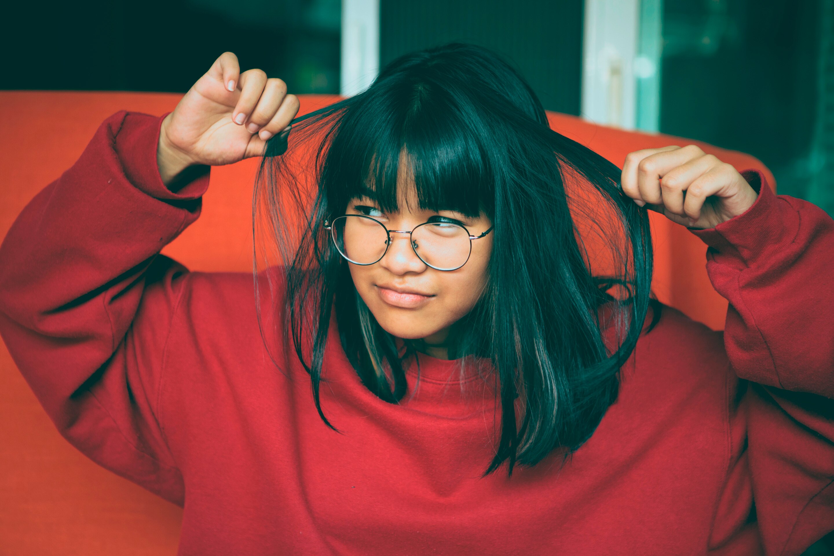Asian woman with straight fine hair with bangs in red sweater.
