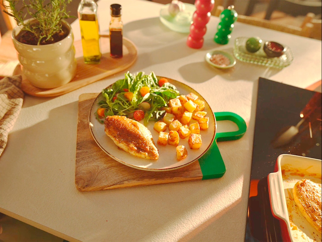 Chicken mit Charakter Rezeptbild Das Gericht ist auf einem Teller und dieser steht auf einem Brett.