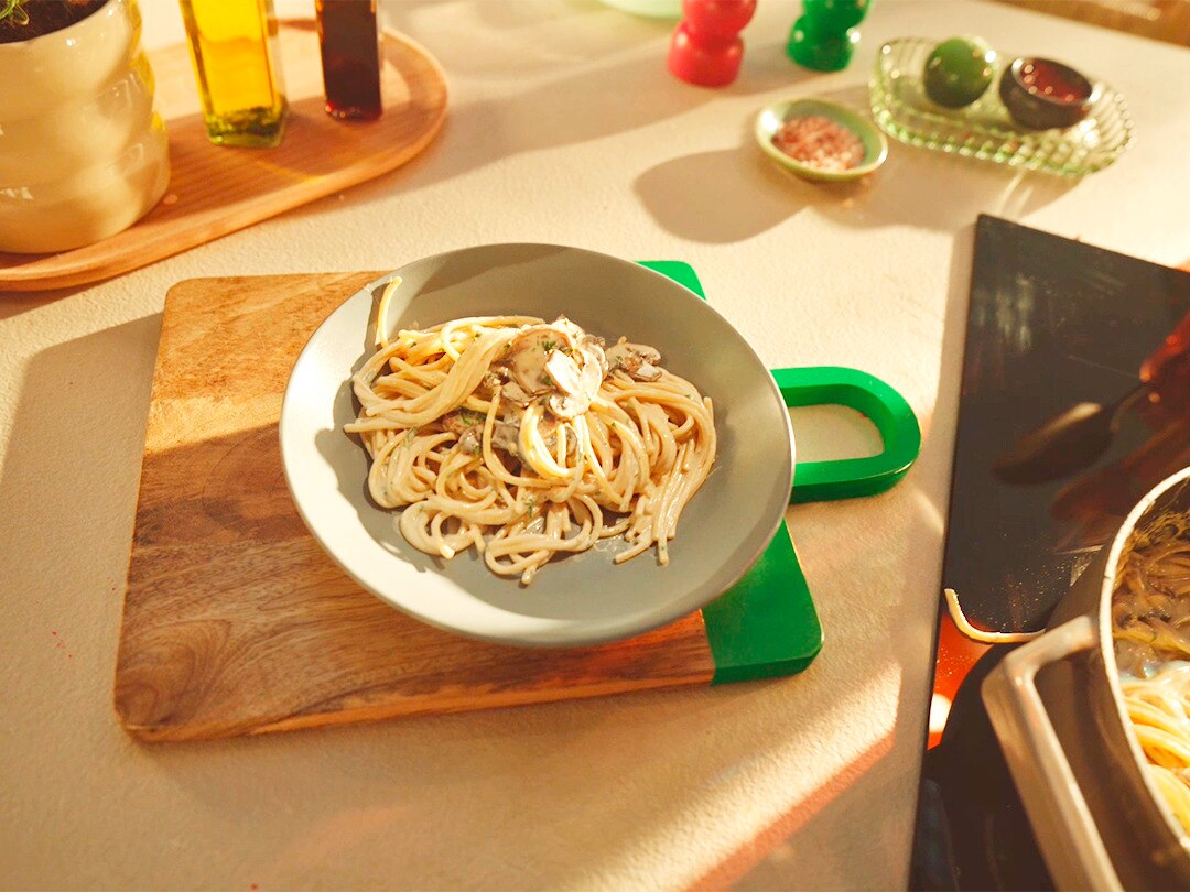 Cremige Knoblauch-Pilz-Pasta Rezeptbild Das Gericht ist auf einem Teller und dieser steht auf einem Brett.