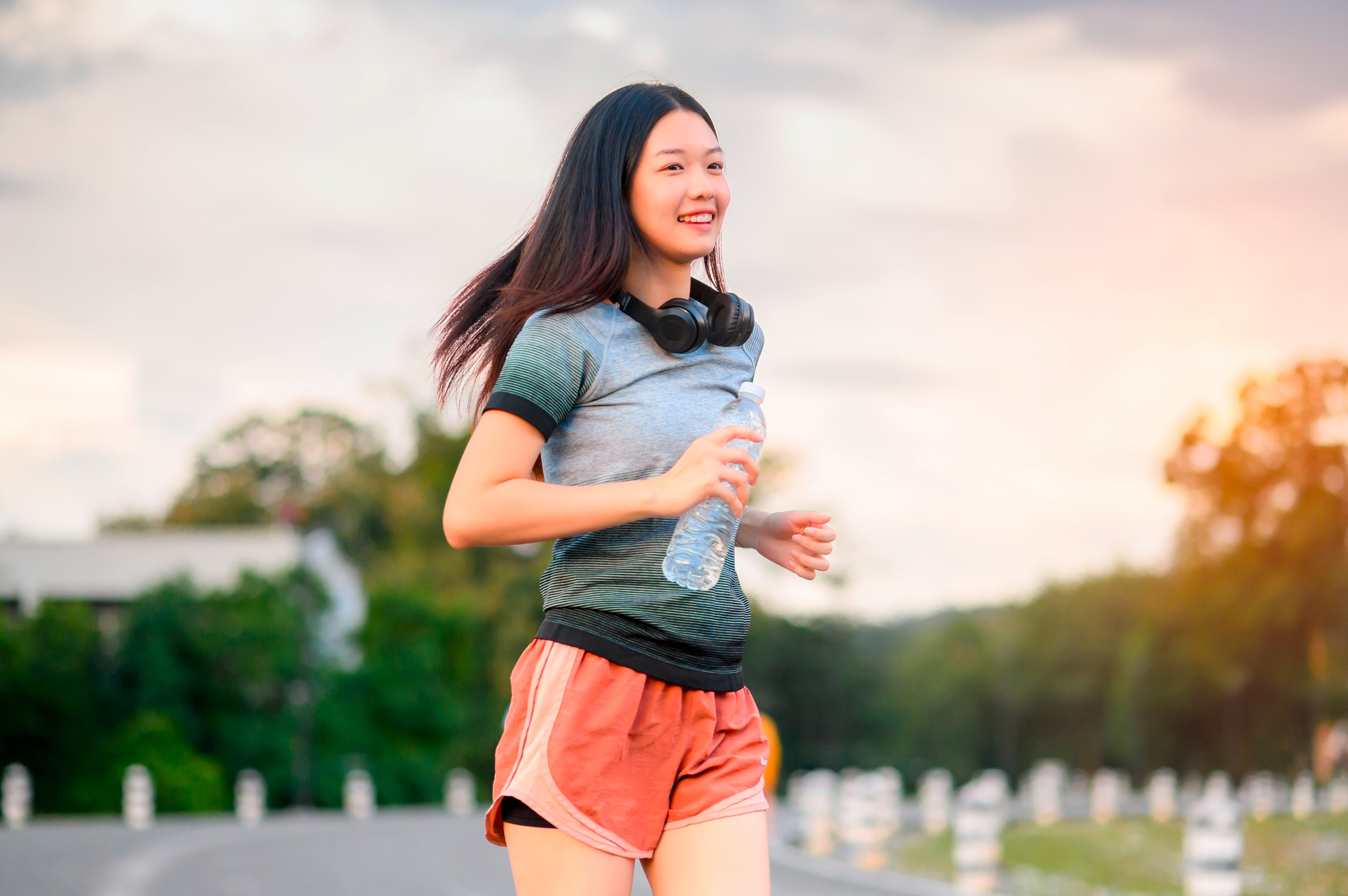 Woman running with earphones and a water bottle.
