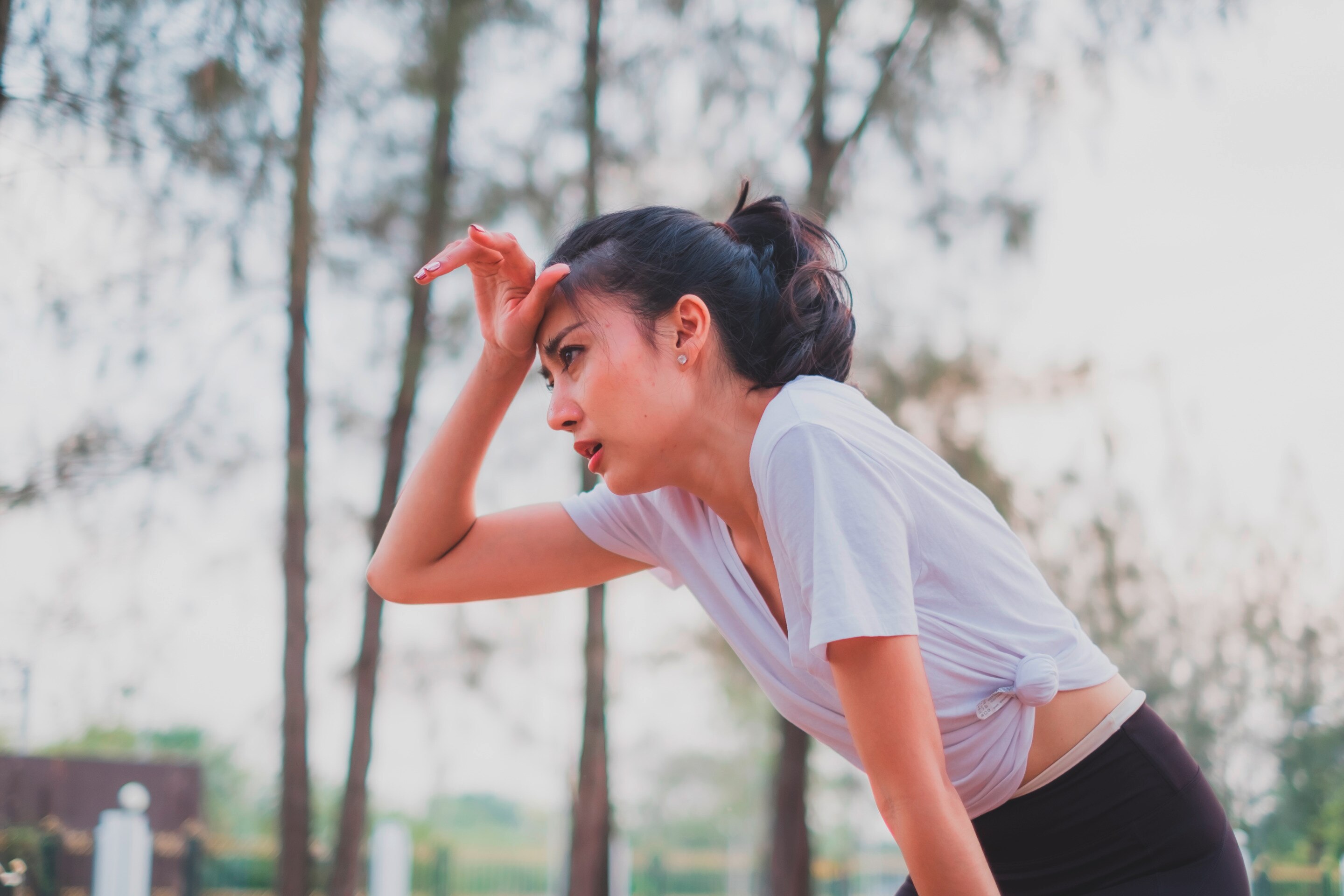 Woman taking a break from running, wiping sweat with hand.
