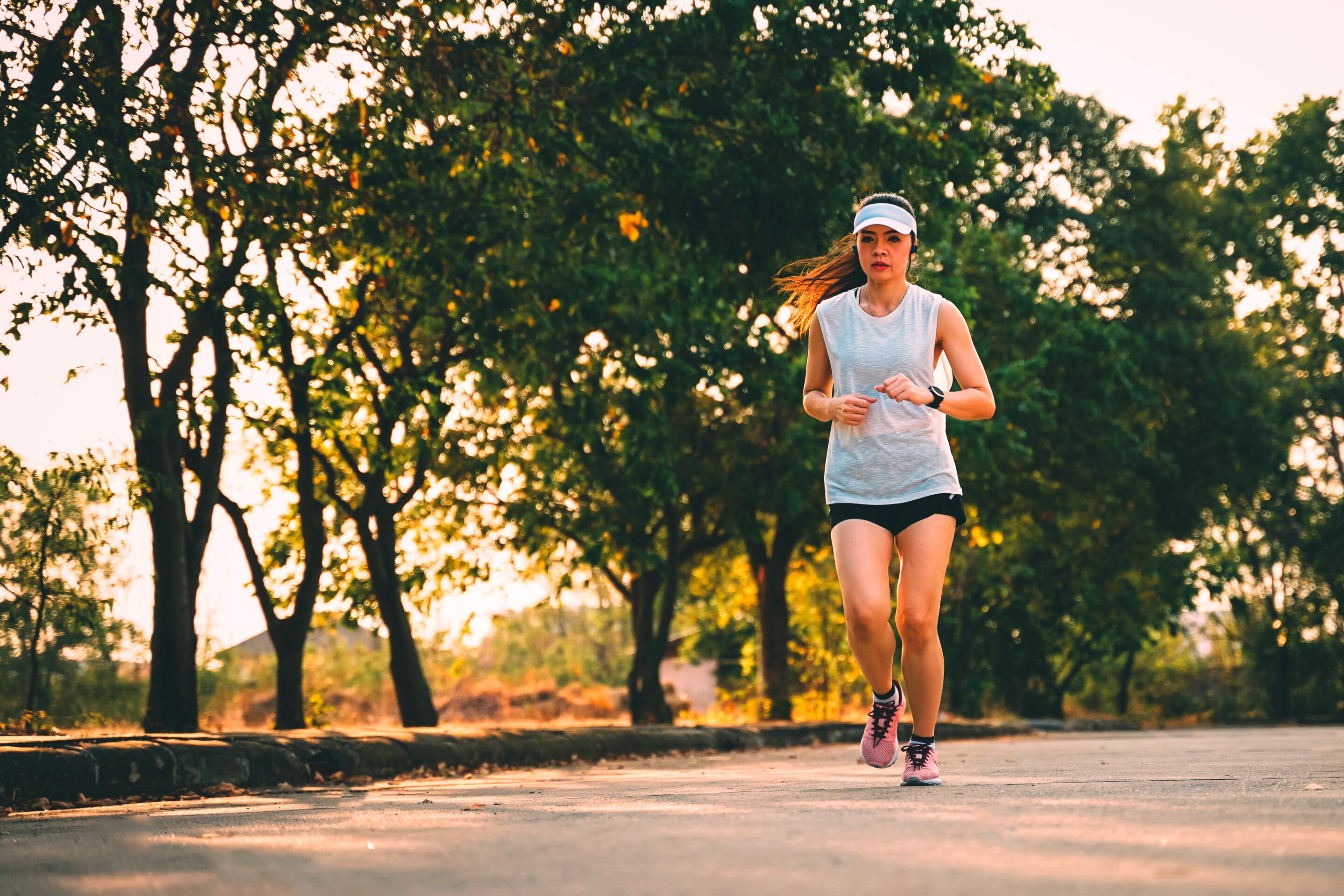 Woman running wearing a cap.