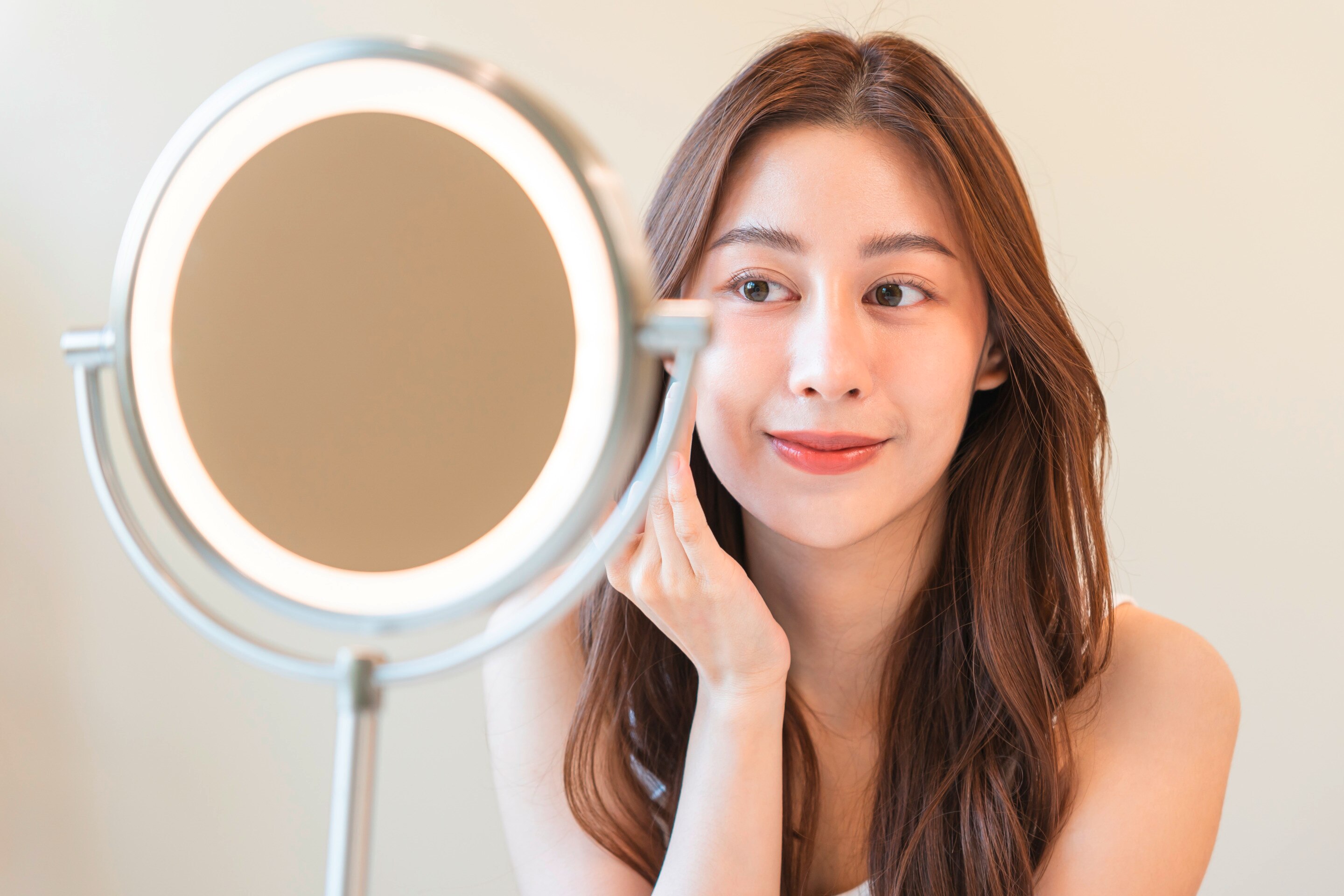 ผู้หญิงเอเชีย รวบหางม้าต่ำ หลับตา สองมือมีโฟมล้างหน้า แตะที่แก้ม จมูกมีฟองโฟม