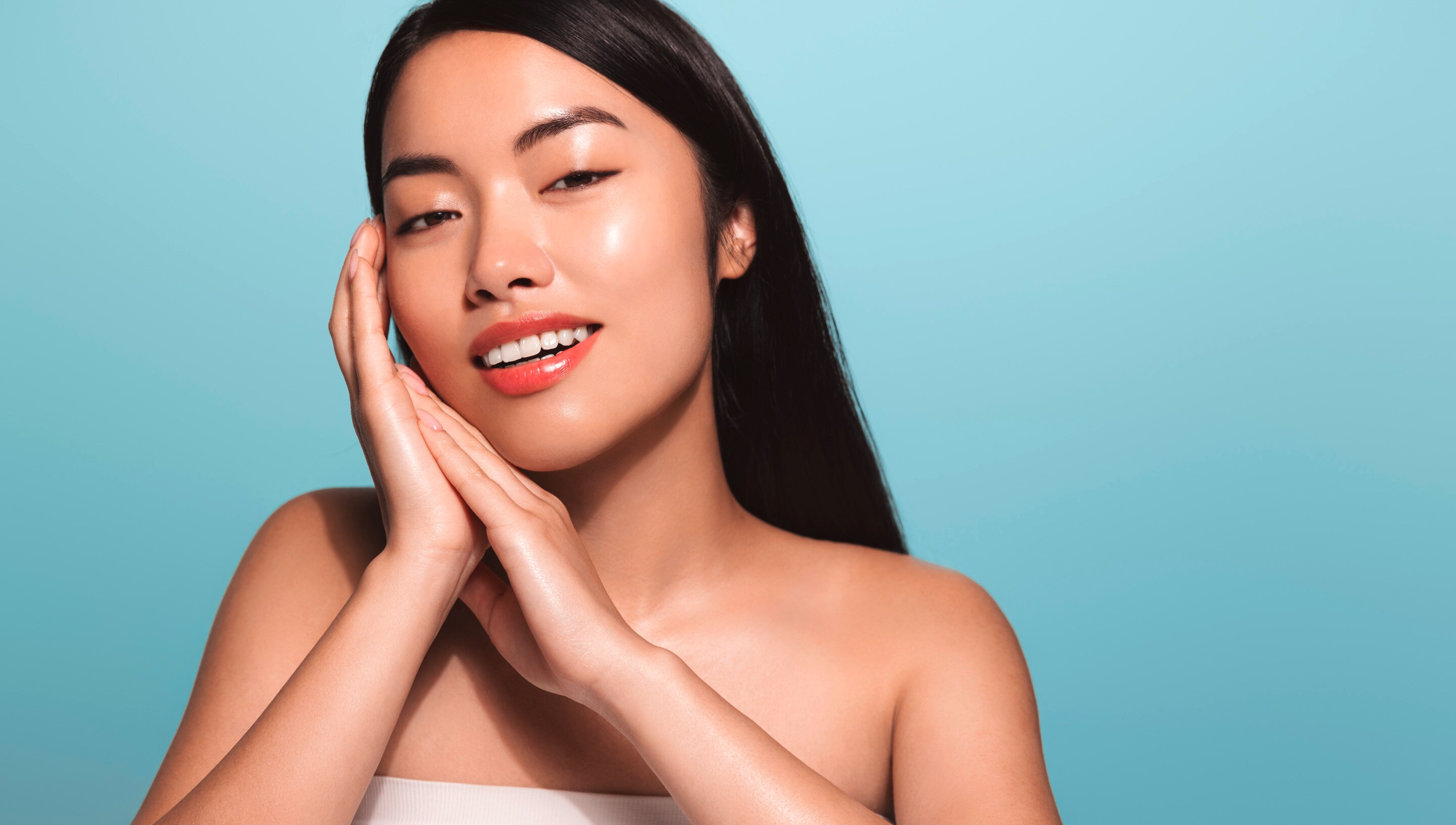 ผู้หญิงเอเชีย ผมดำ ผมตรงยาว ผิวสวยใส ยิ้มเห็นฟัน สองมือประกบ มือประคองหน้า สวมเกาะอกสีขาว