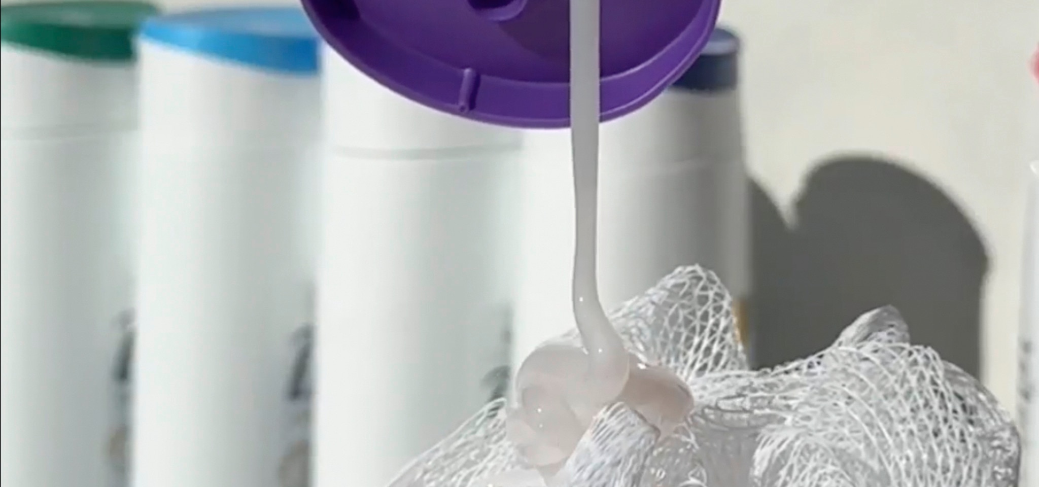 Dove body wash being poured onto a white loofah.