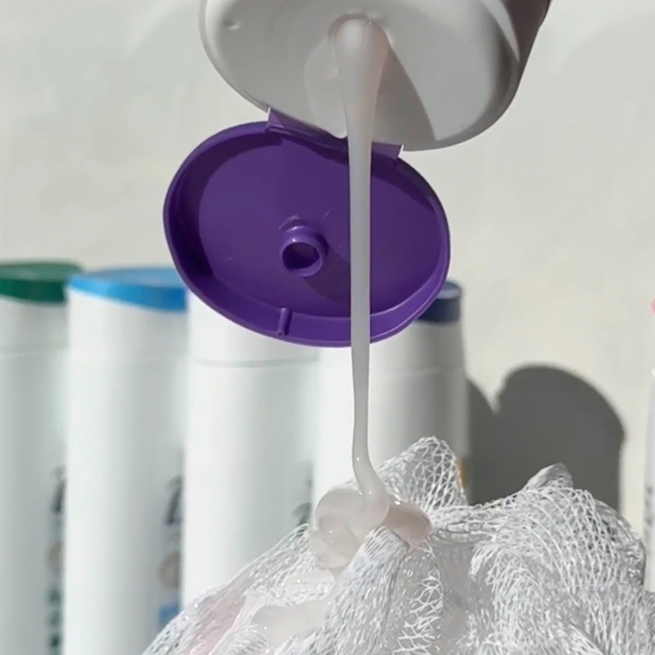 Dove body wash being poured onto a white loofah.