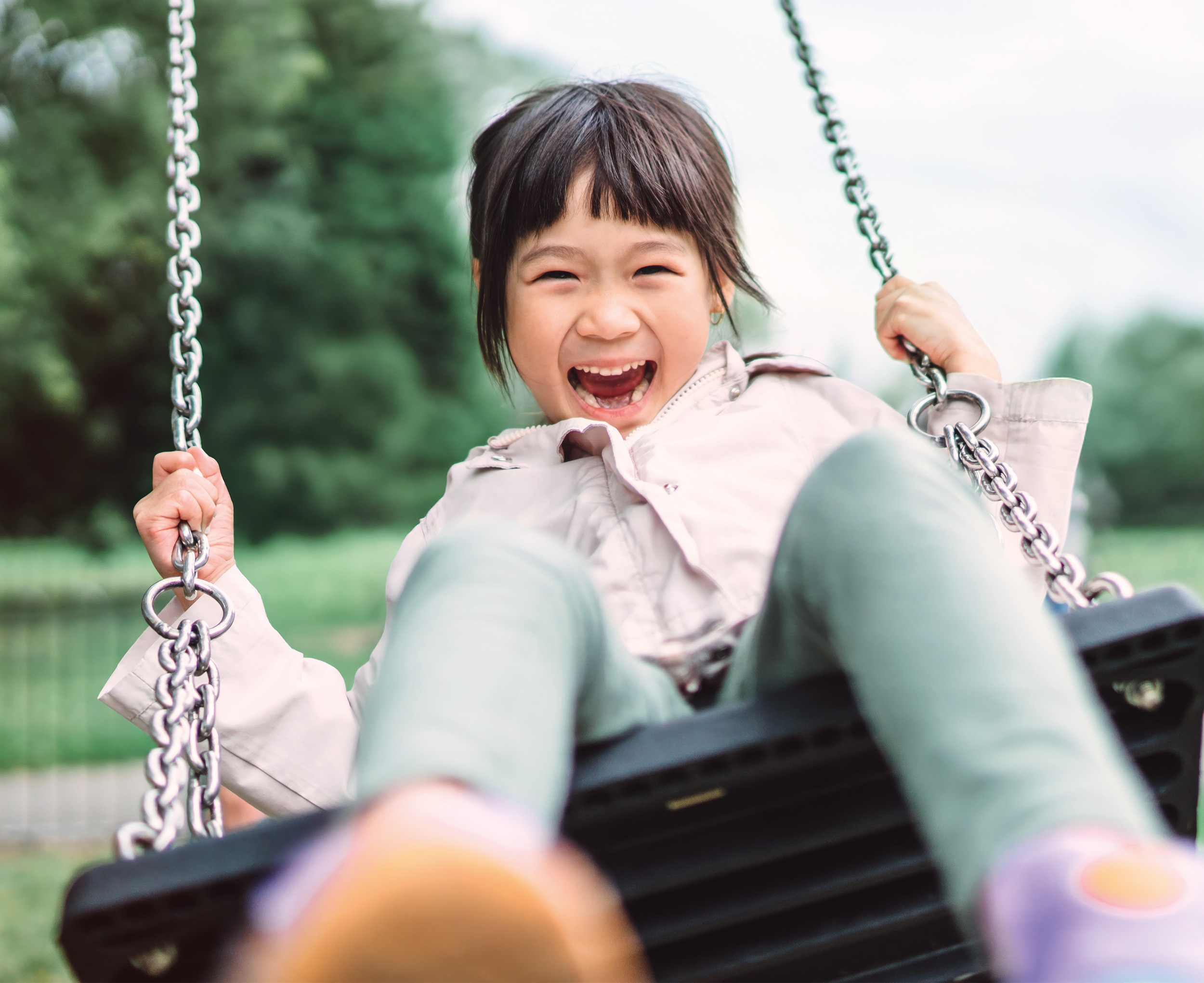 Young girl smiling whilst playing on a swing