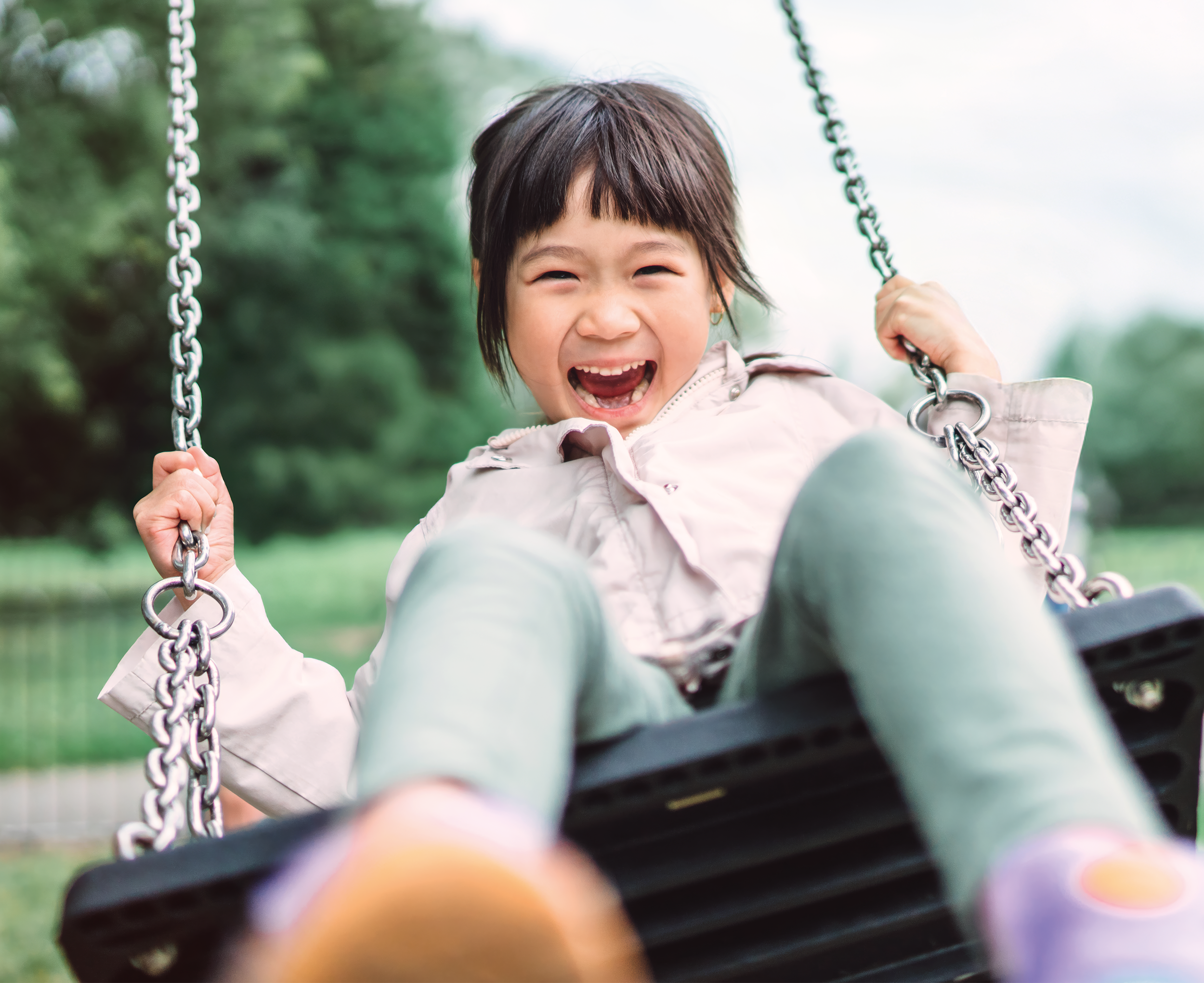 Girl swinging on a swing laughing 