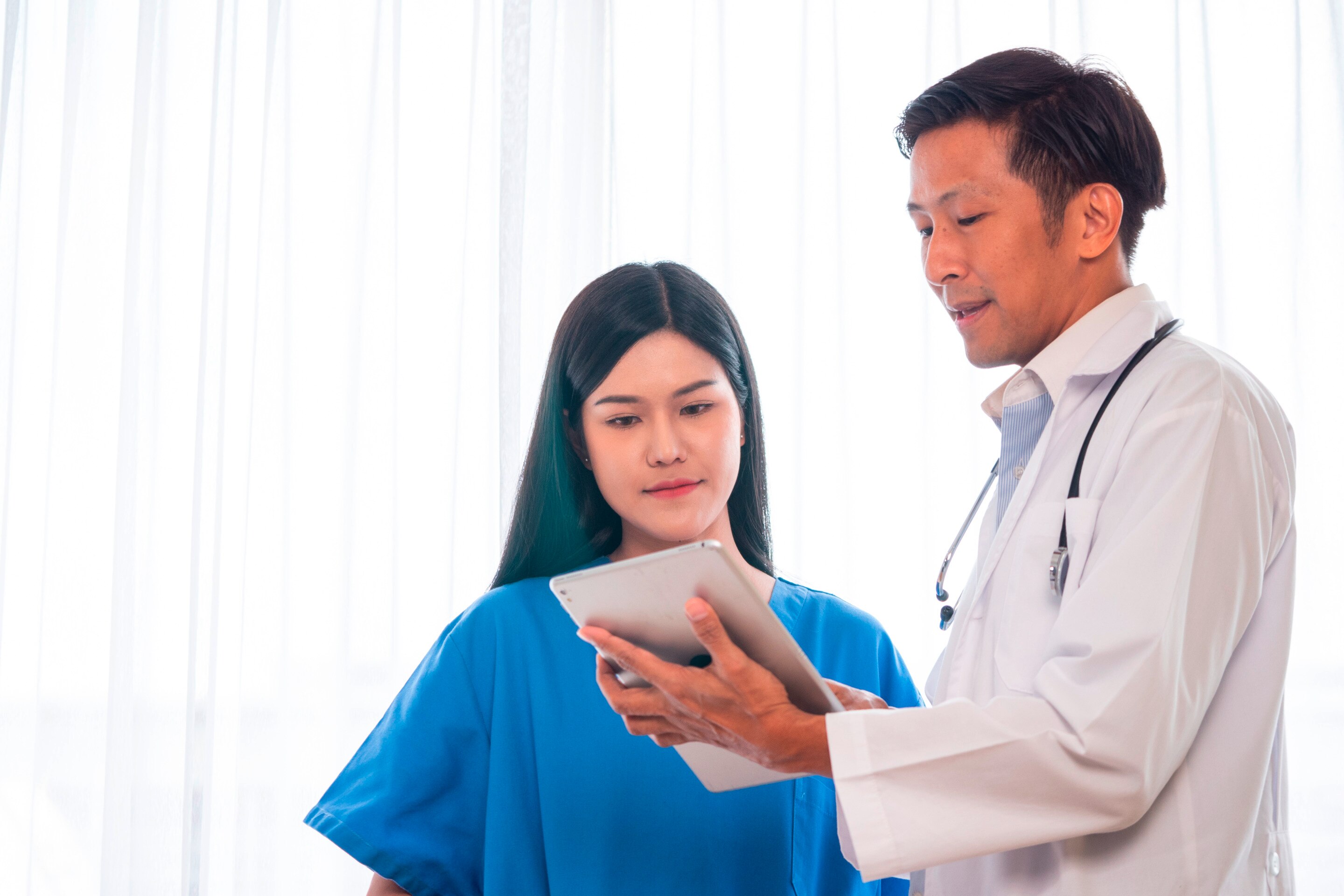 A male doctor showing his tablet to his female patient.