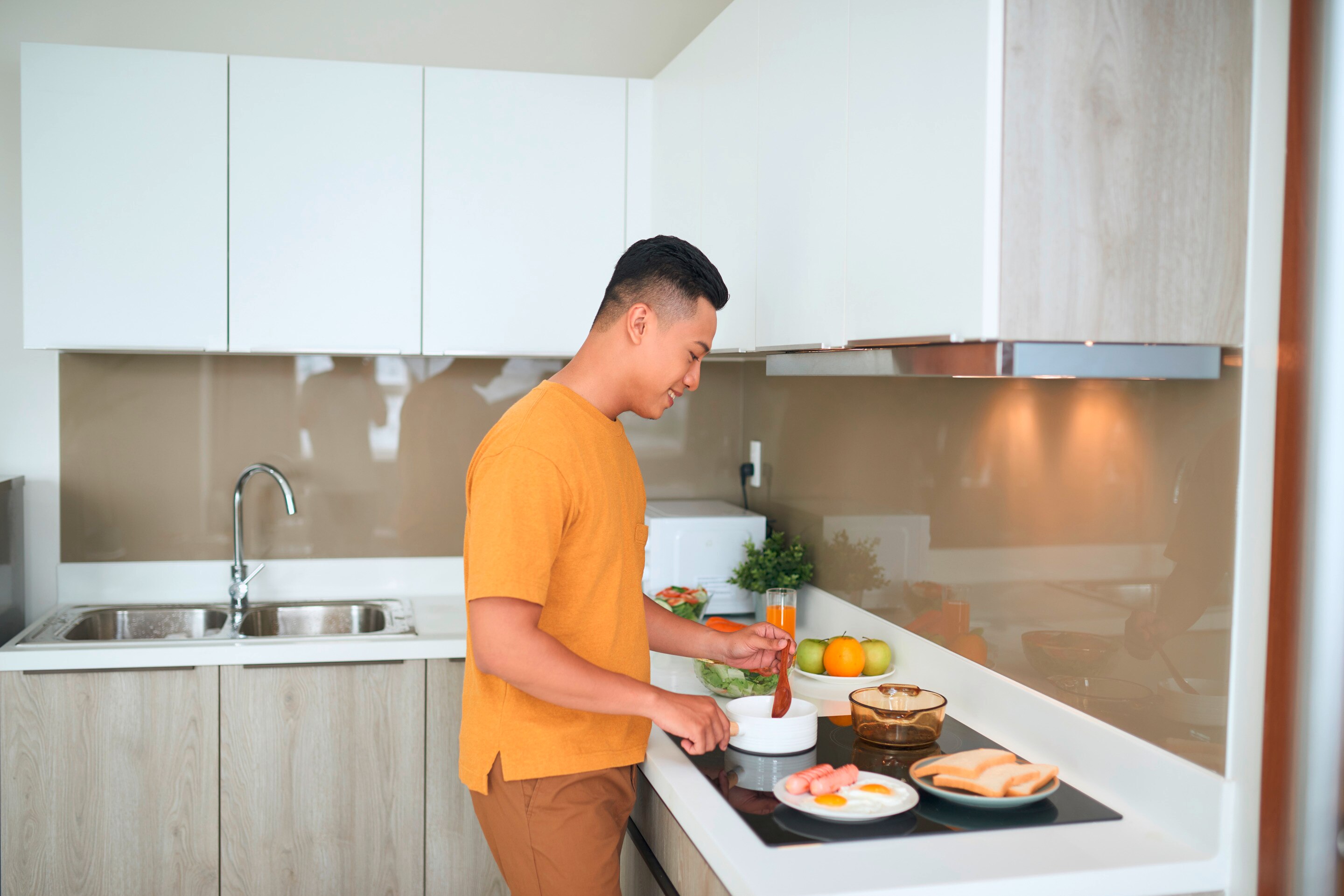 Happy Asian man cooking at home.