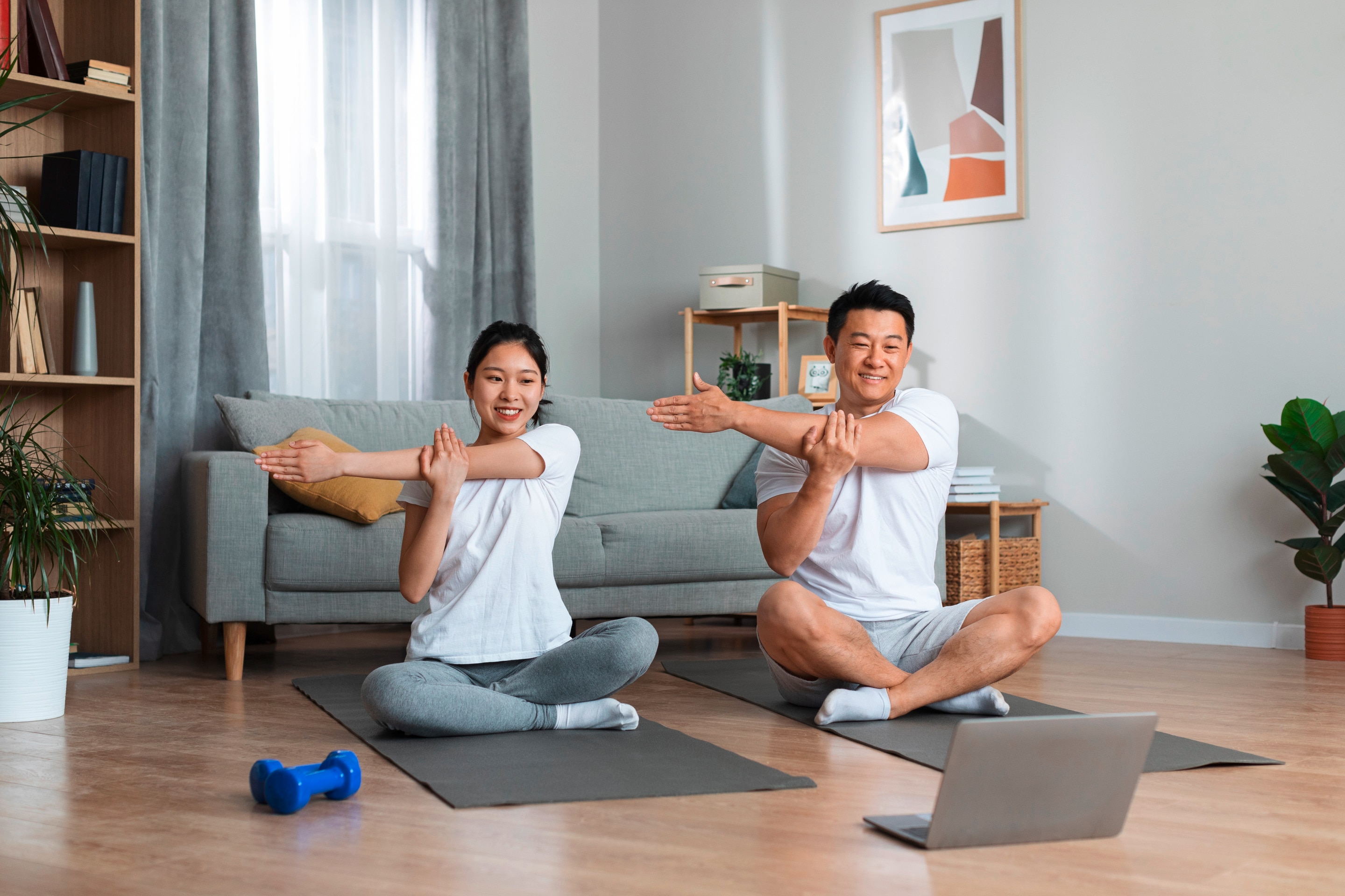 Happy couple in sportswear sitting on fitness mats while doing yoga together. 
