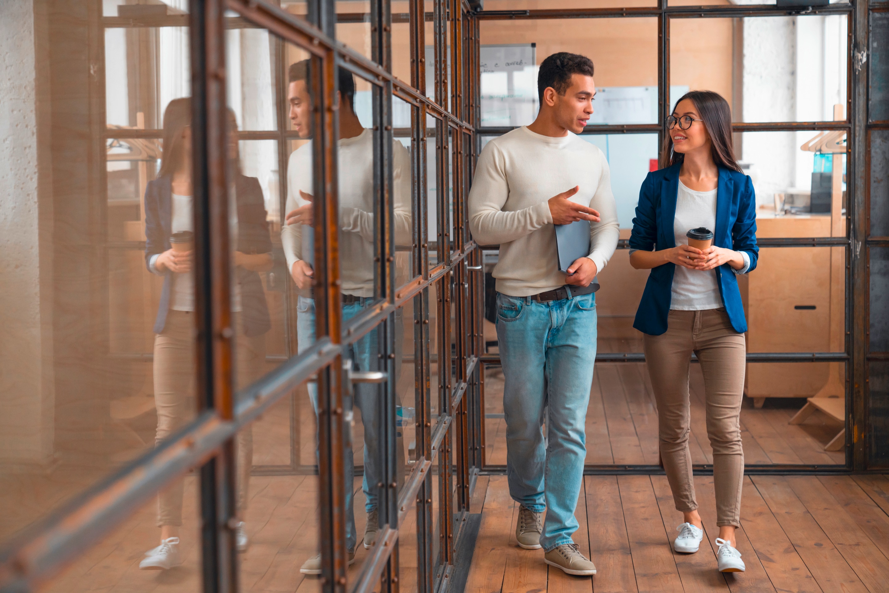 Two business people walking while talking about work questions.