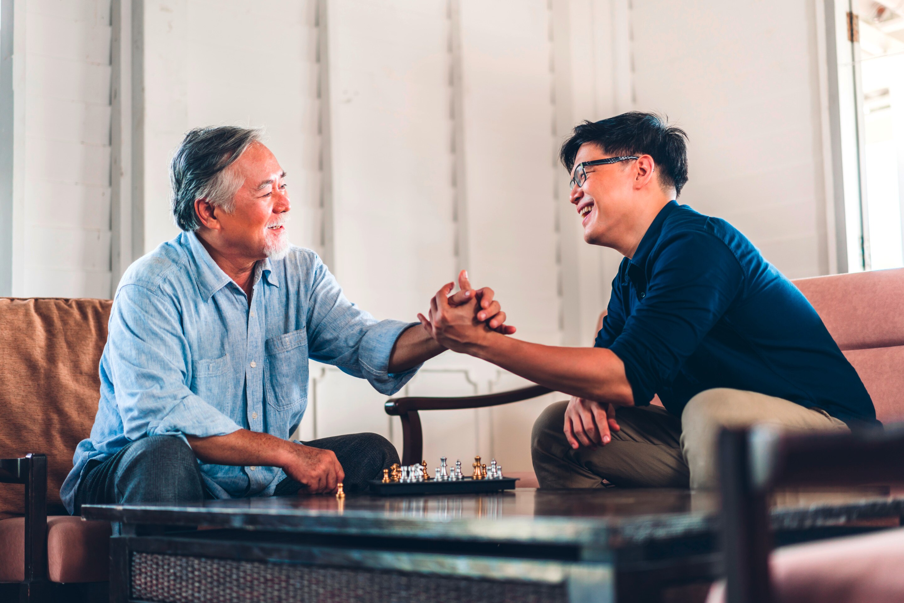 Two men shaking hands while smiling at each other.