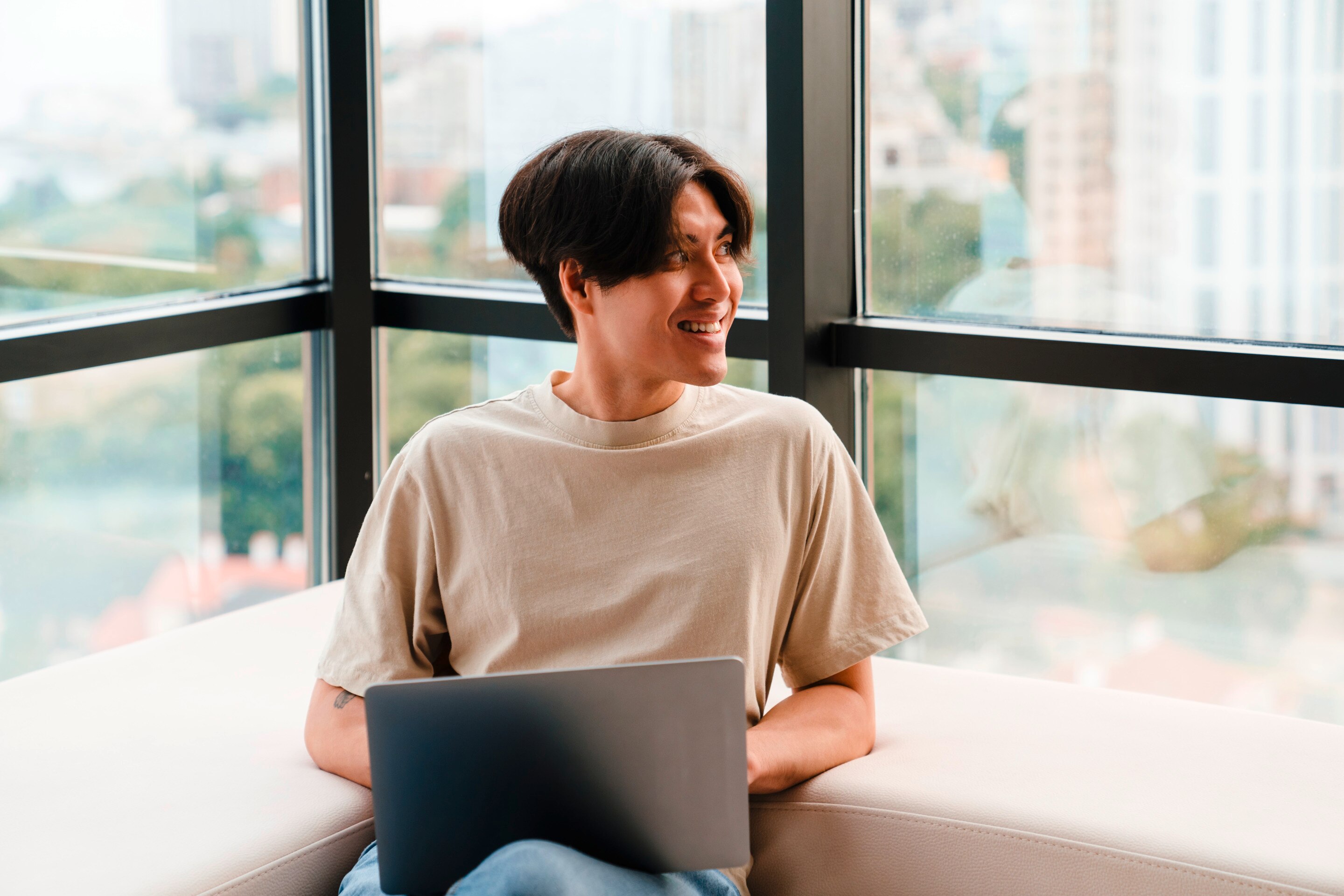 Smiling man in T-shirt working on his laptop.