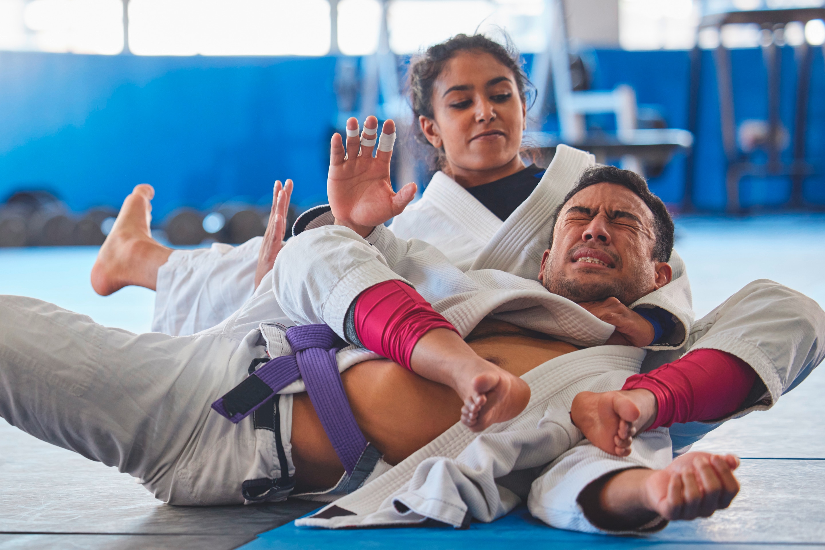 Woman pins down a man in jiu-jitsu.