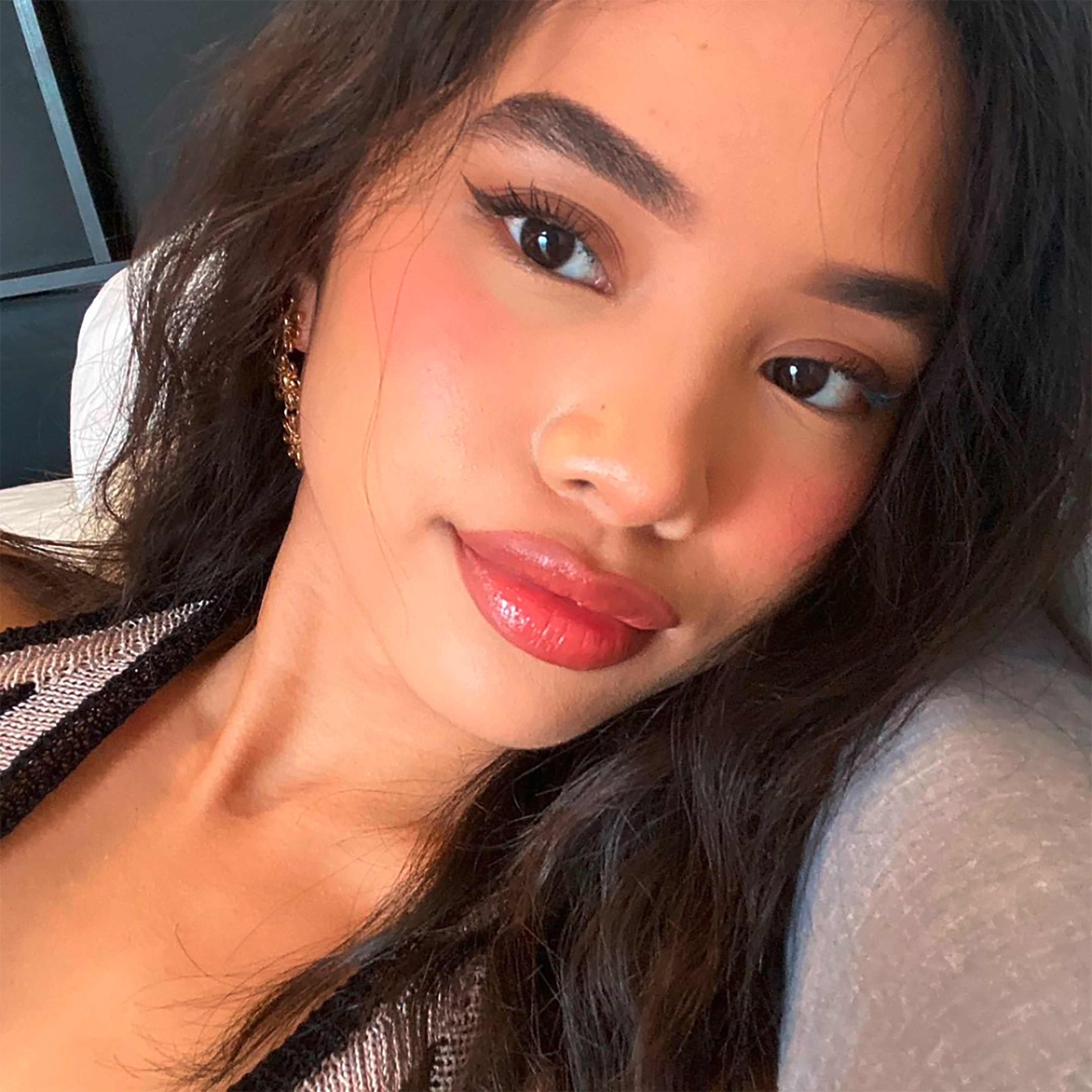 A selfie of woman with glossy pink lips and flushed cheeks.