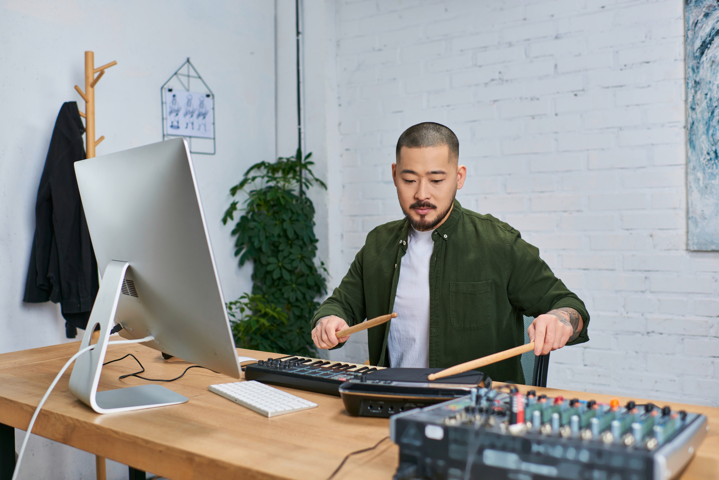 Man making music using drum pads in home studio.