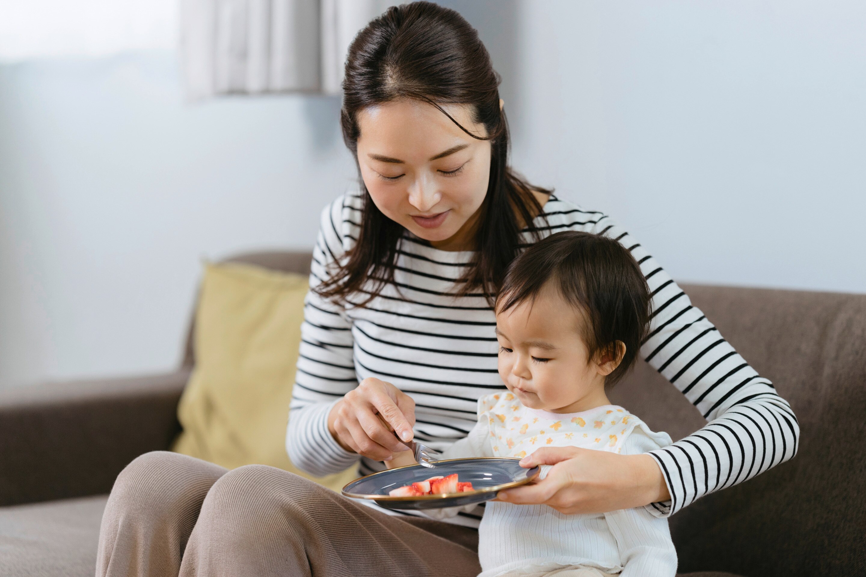 Mom feeding her child fruits.
