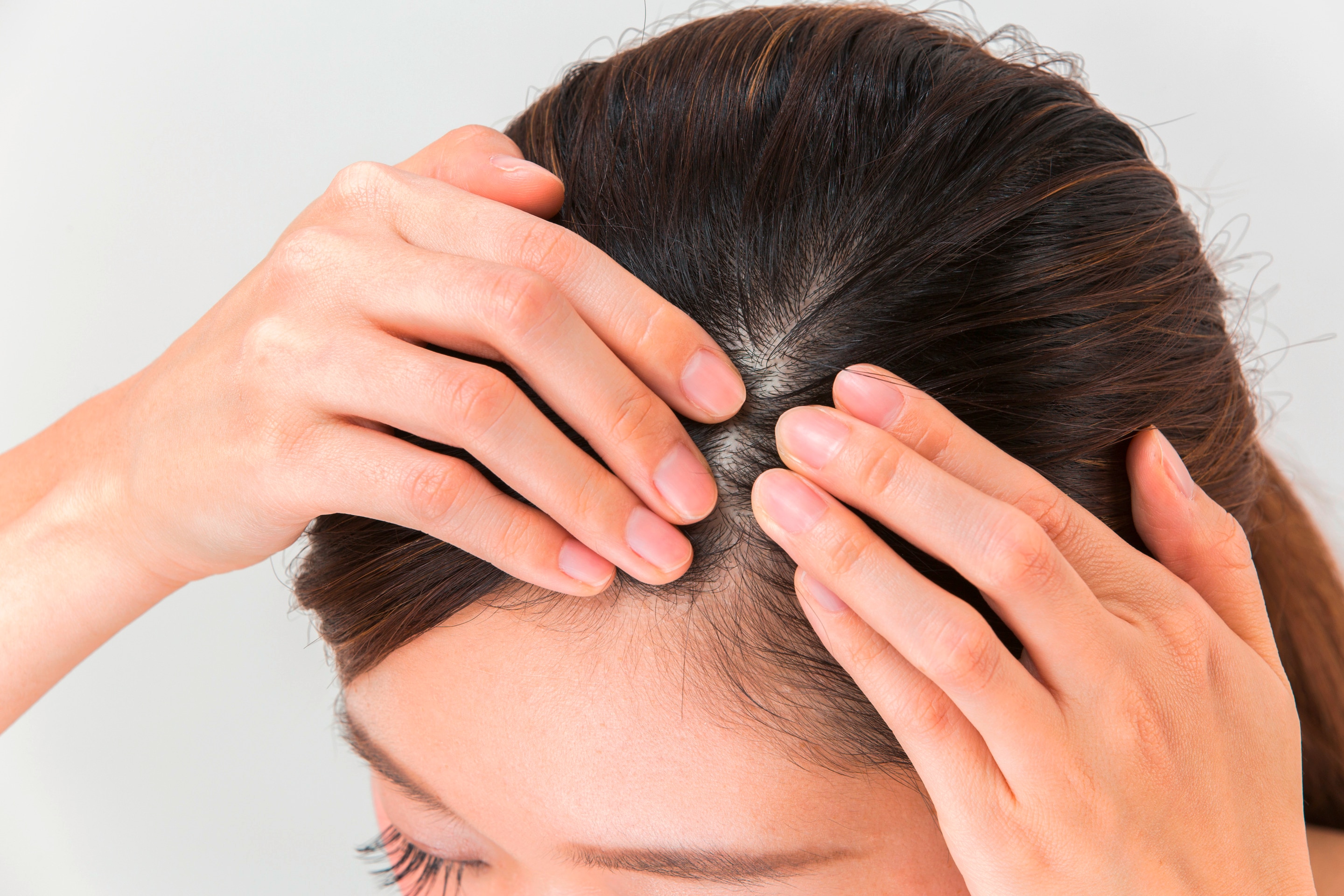 Asian woman massaging scalp.