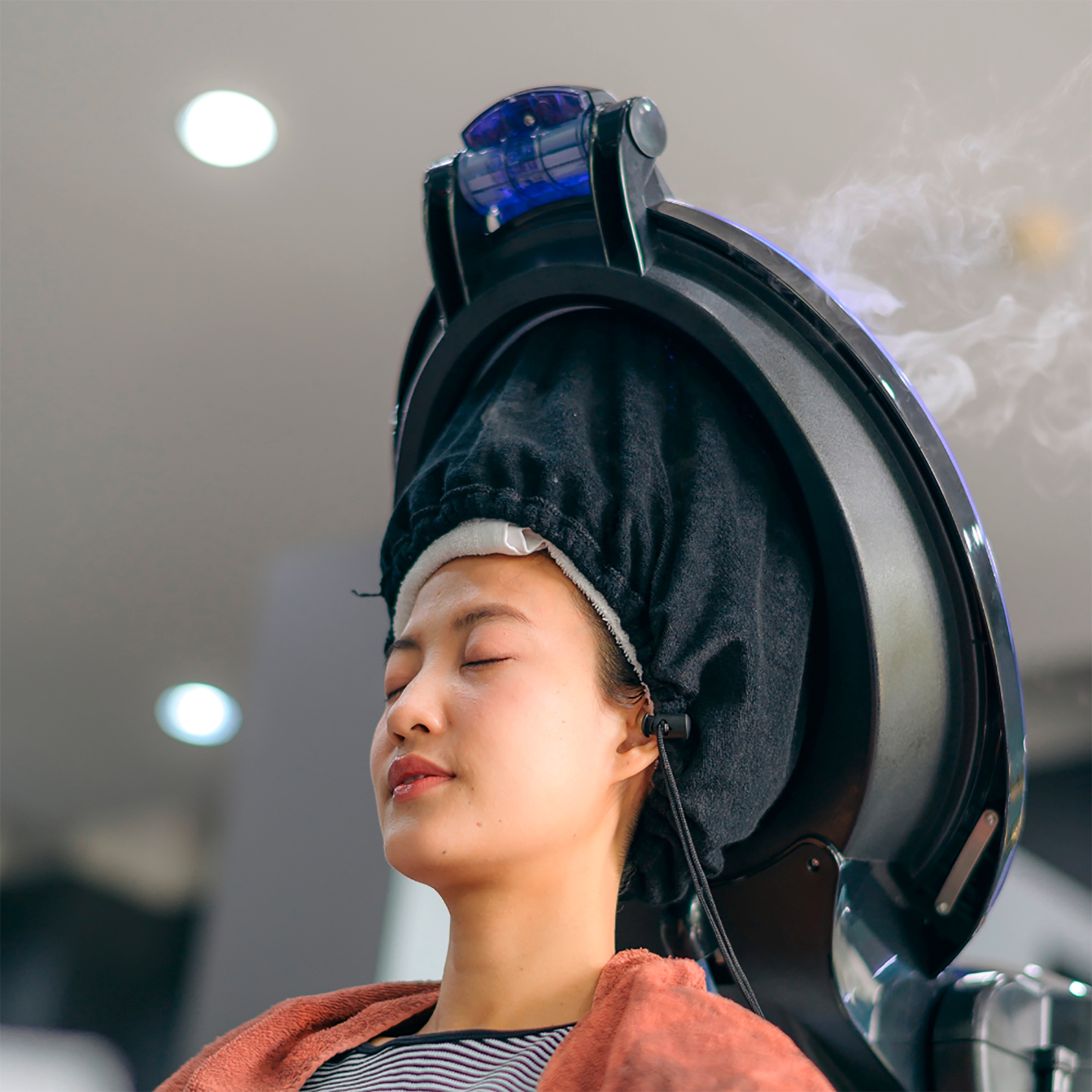 An Asian woman relaxes while getting a hair treatment