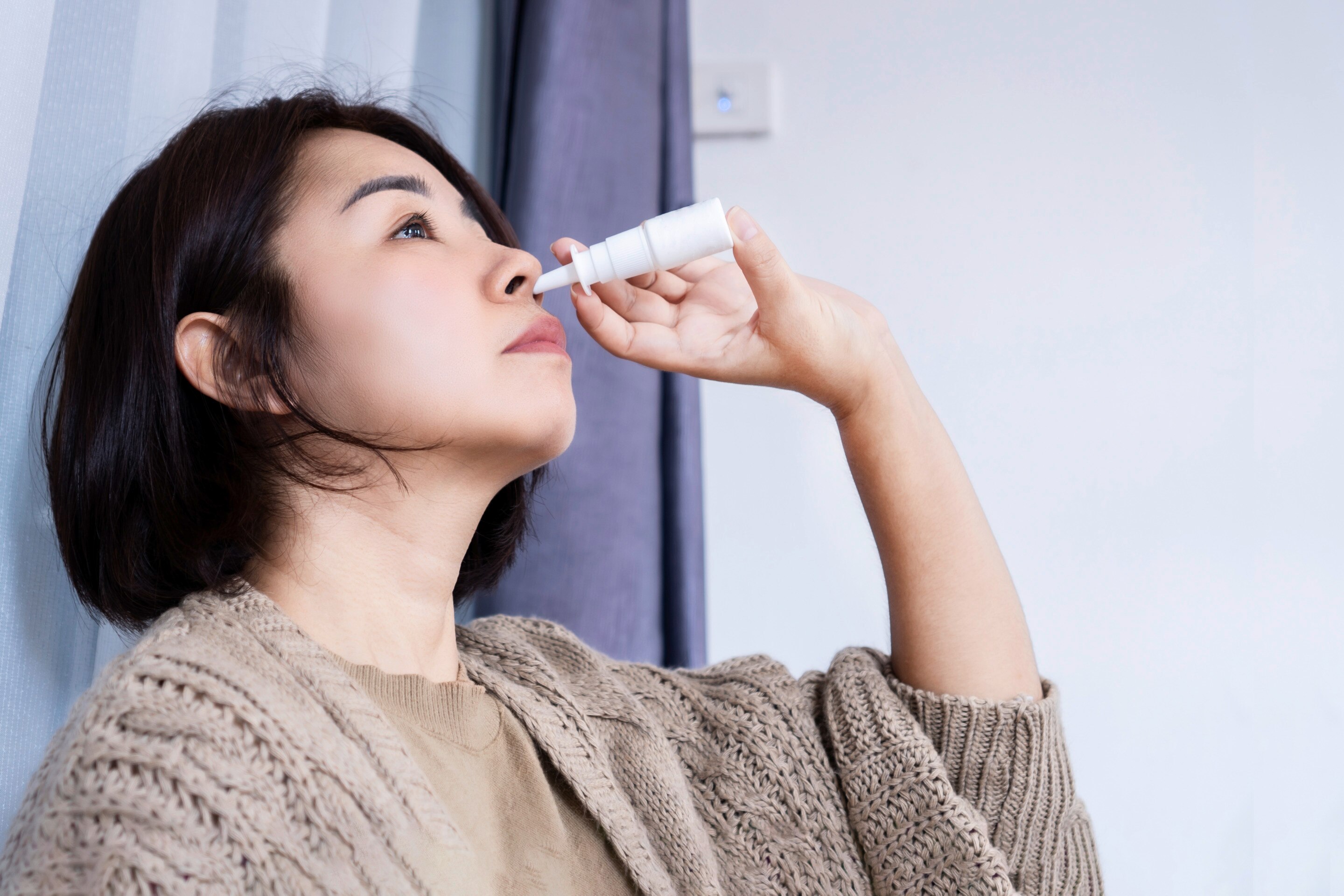 Woman using a nasal spray.