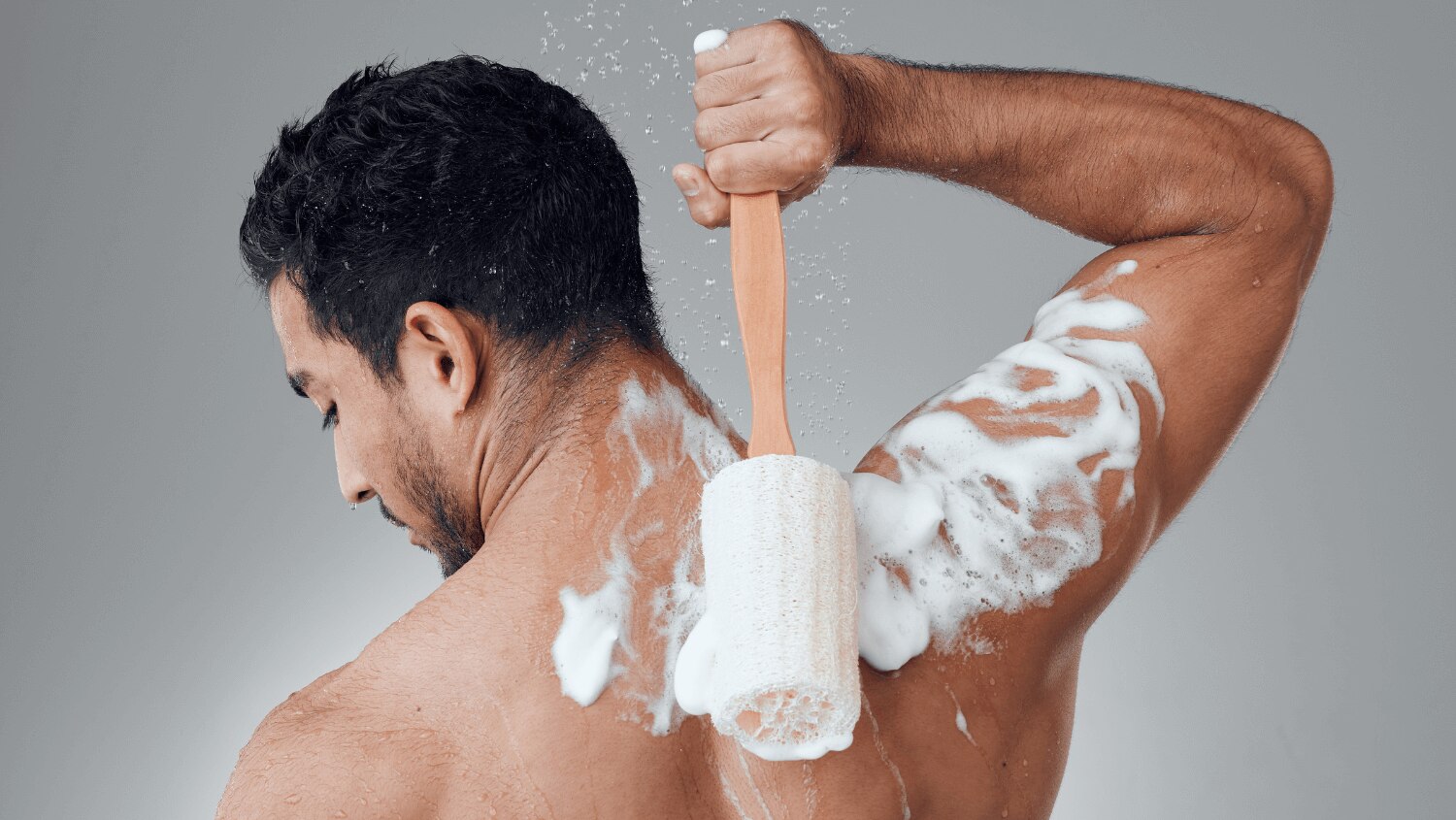 Man in shower exfoliating with a loofah