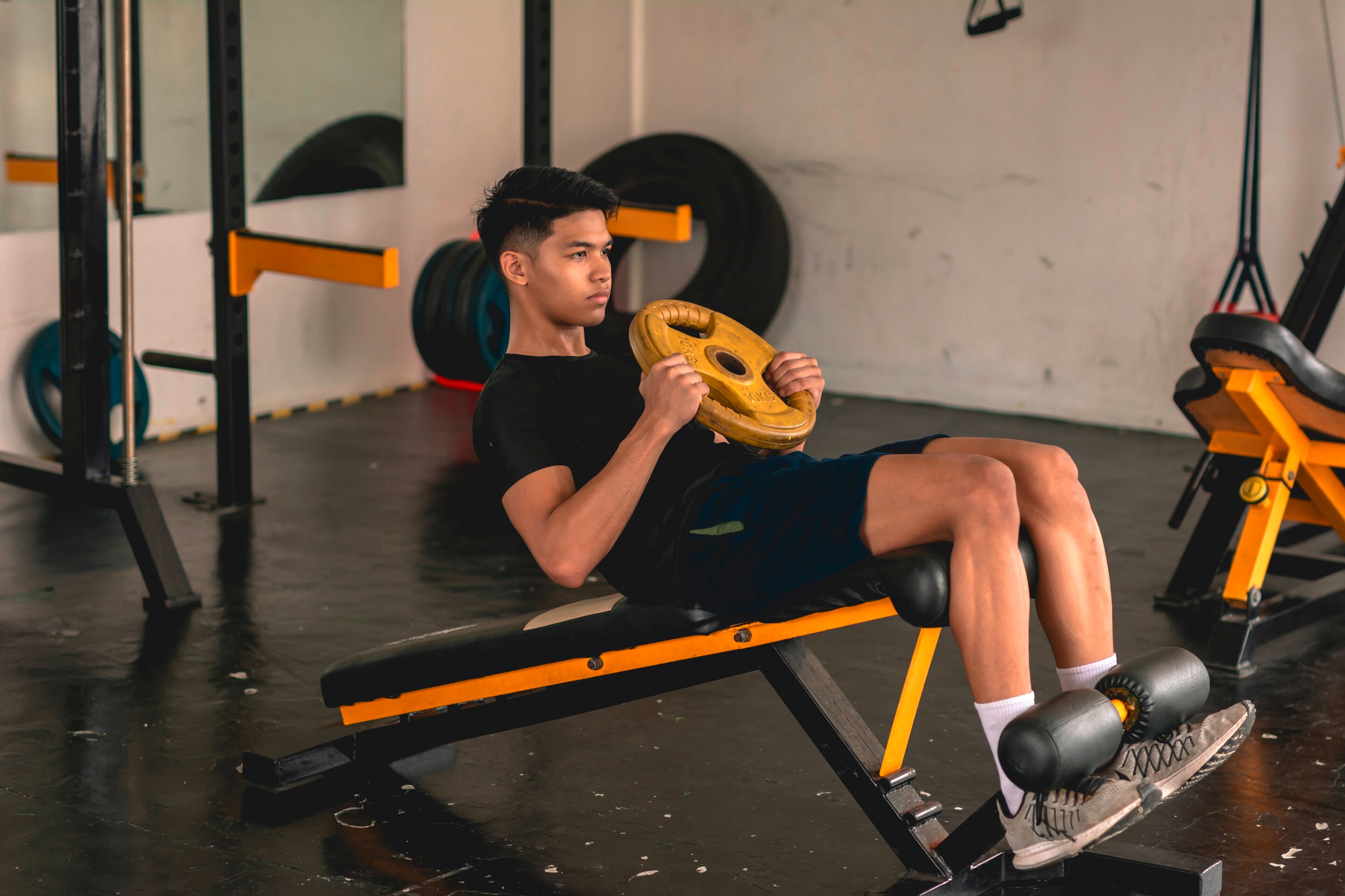 Man holds a weighted plate while doing sit-ups.