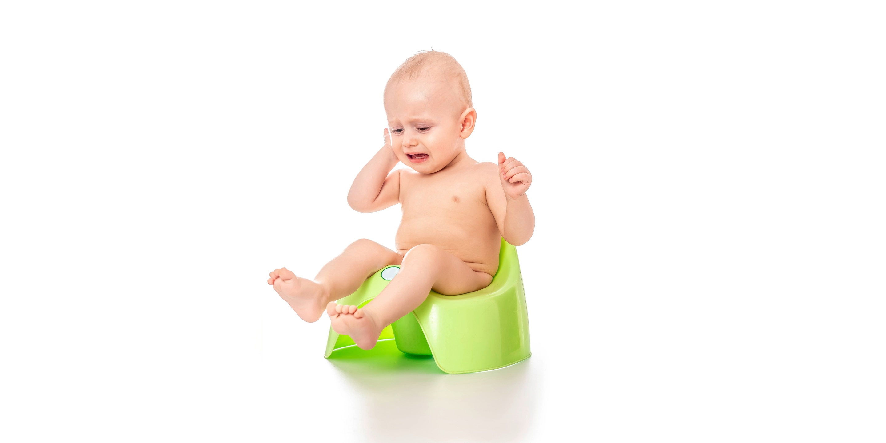 Bayi duduk di potty training warna hijau sambil menangis karena sedang sembelit
