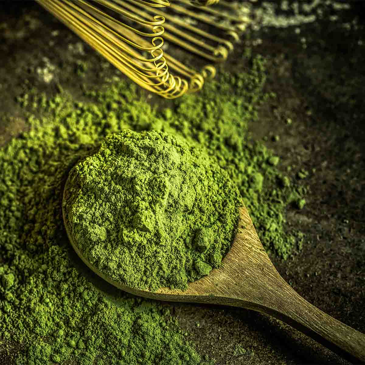 Wooden spoon with matcha powder and bamboo whisk
