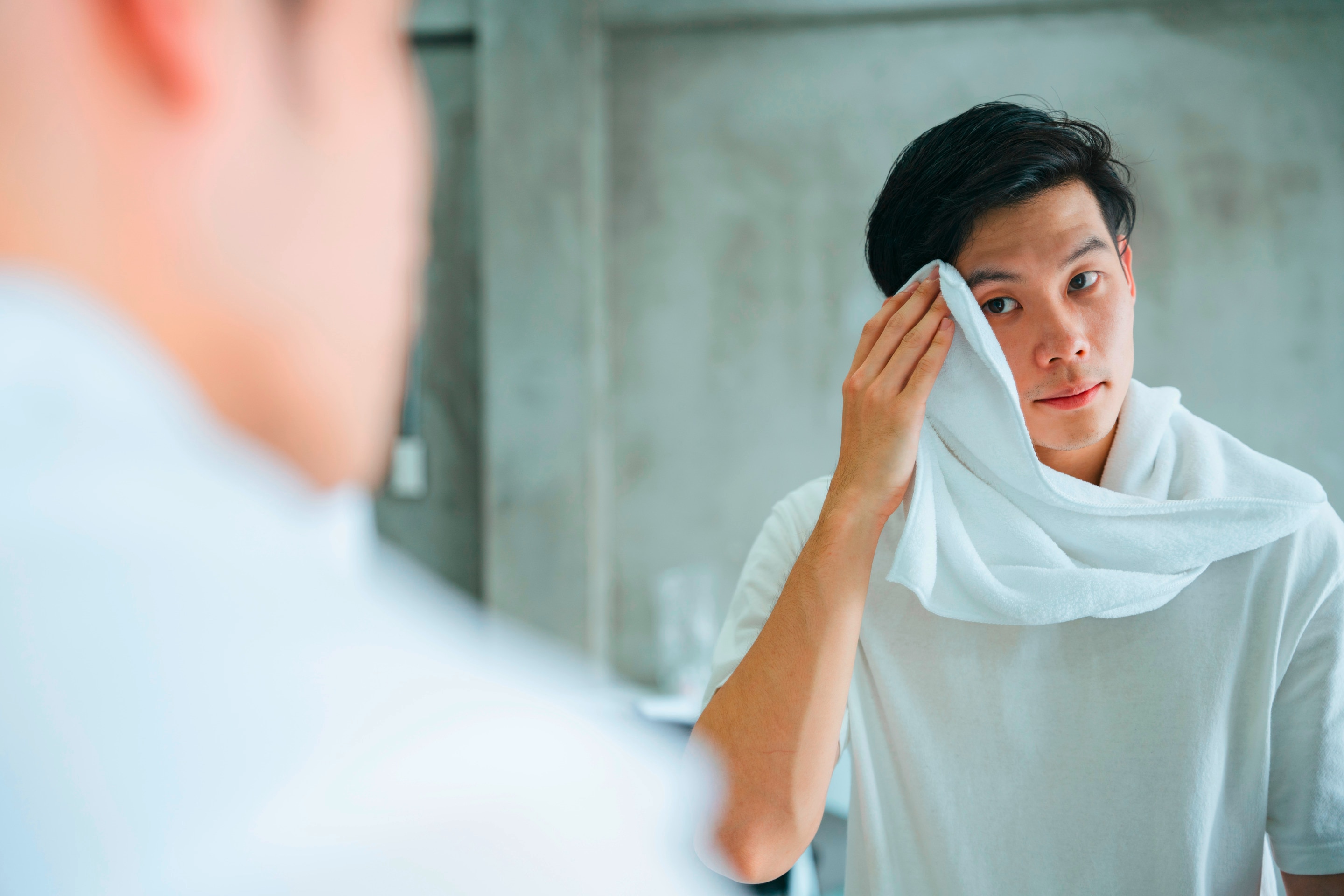Man patting his face with a towel.